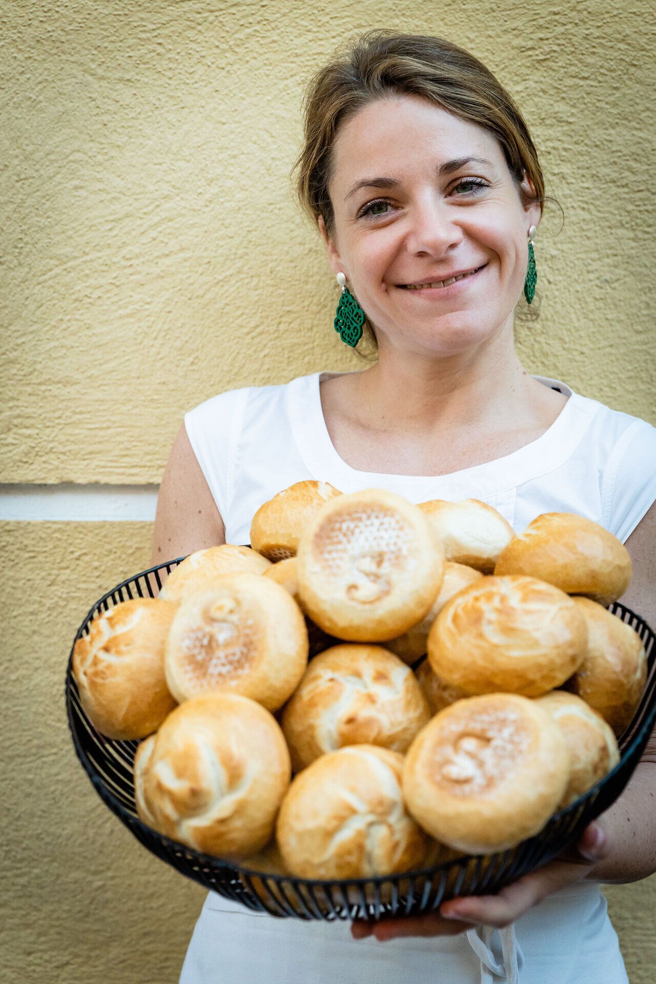 In der malerischen Umgebung von Dürnstein strahlt die Bäckerin mit einem Korb voller frisch gebackener Wachauer Laberl. Der Duft von warmem Brot und die herzliche Atmosphäre laden dazu ein, die kulinarischen Köstlichkeiten der Region zu genießen.