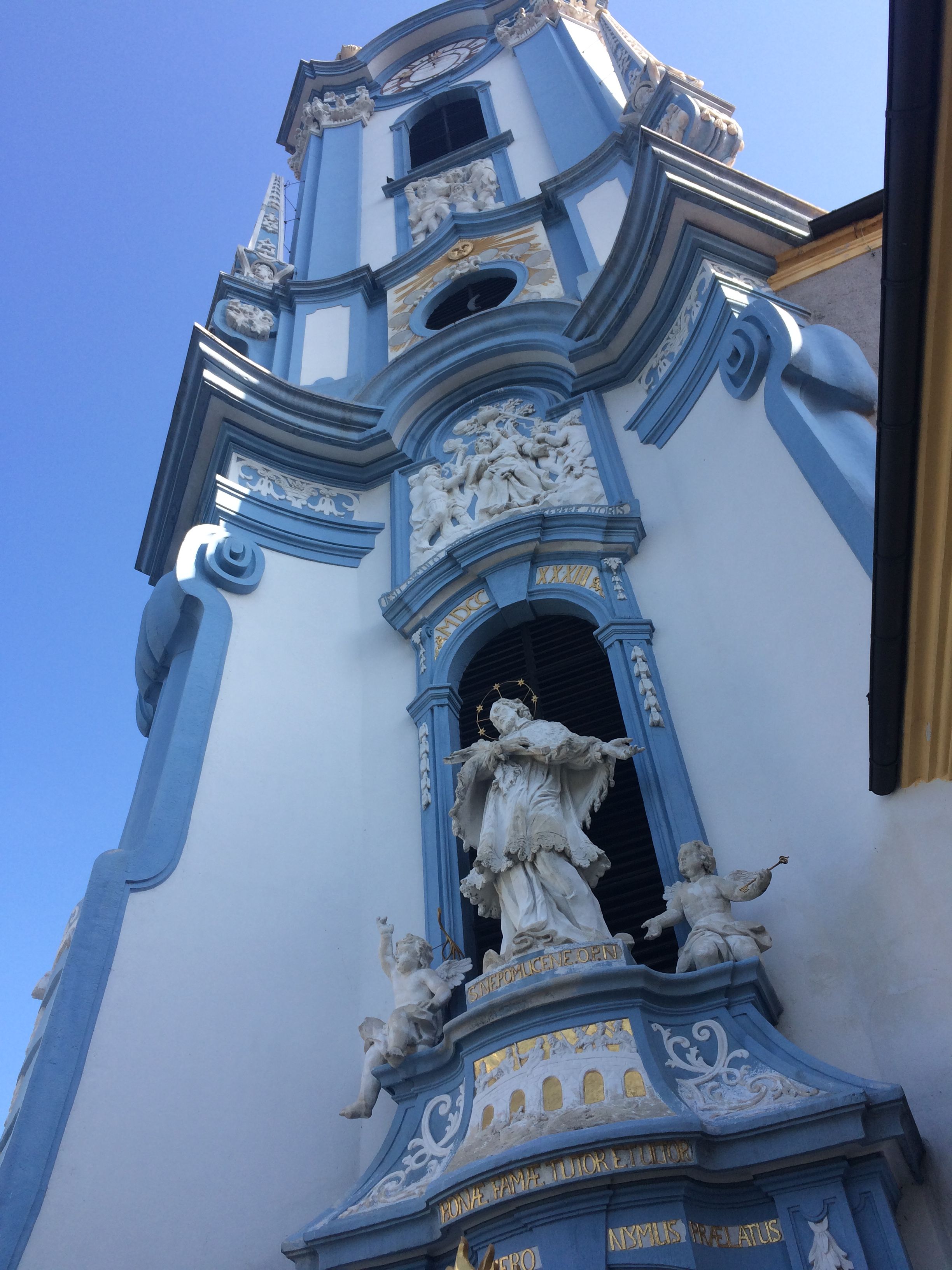 Blauer Turm der Stiftskirche in Dürnstein mit barocken Verzierungen und Statuen.