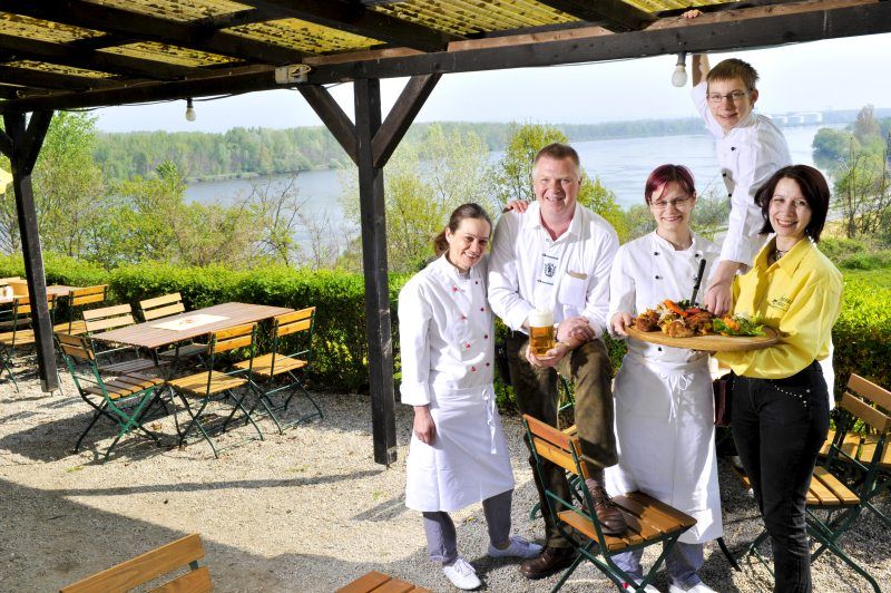Ein Team von fünf Personen in einem Biergarten mit Blick auf einen Fluss.