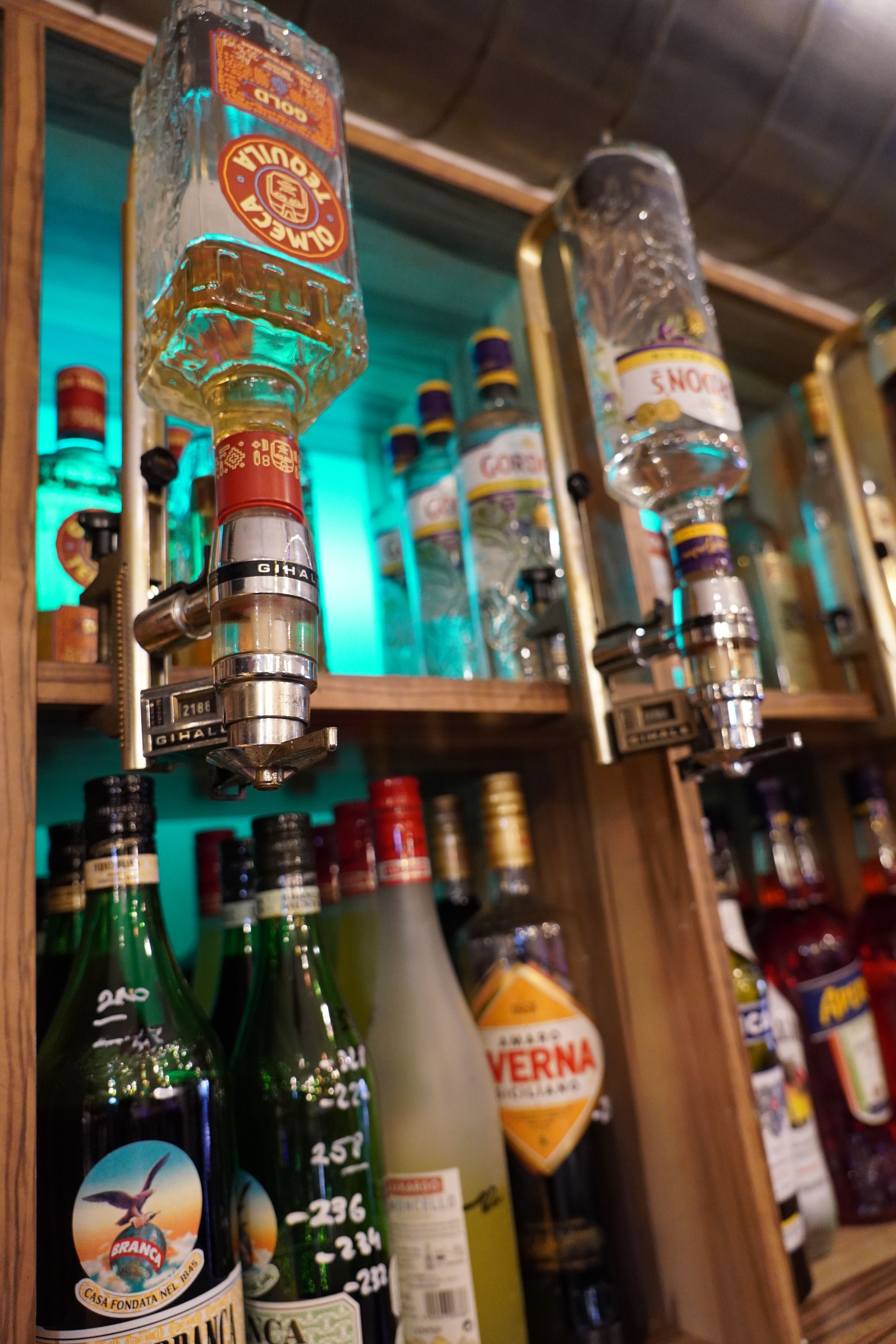 Nahaufnahme von Spirituosenflaschen in einer Bar mit Zapfhähnen.