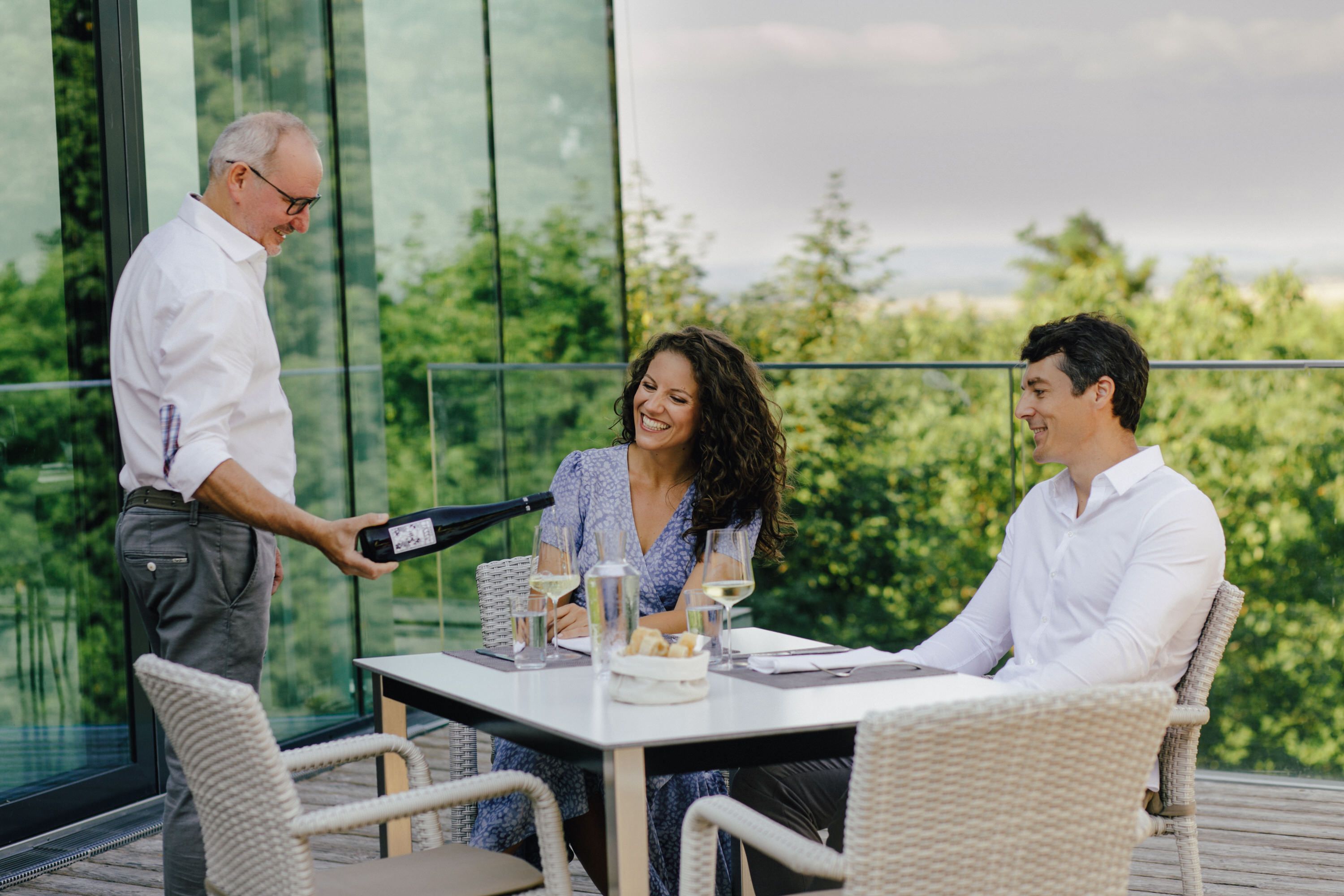 Weinverkostung auf einer Terrasse am Wagram mit Winzer und Gästen bei einem Glas regionalem Wein.
