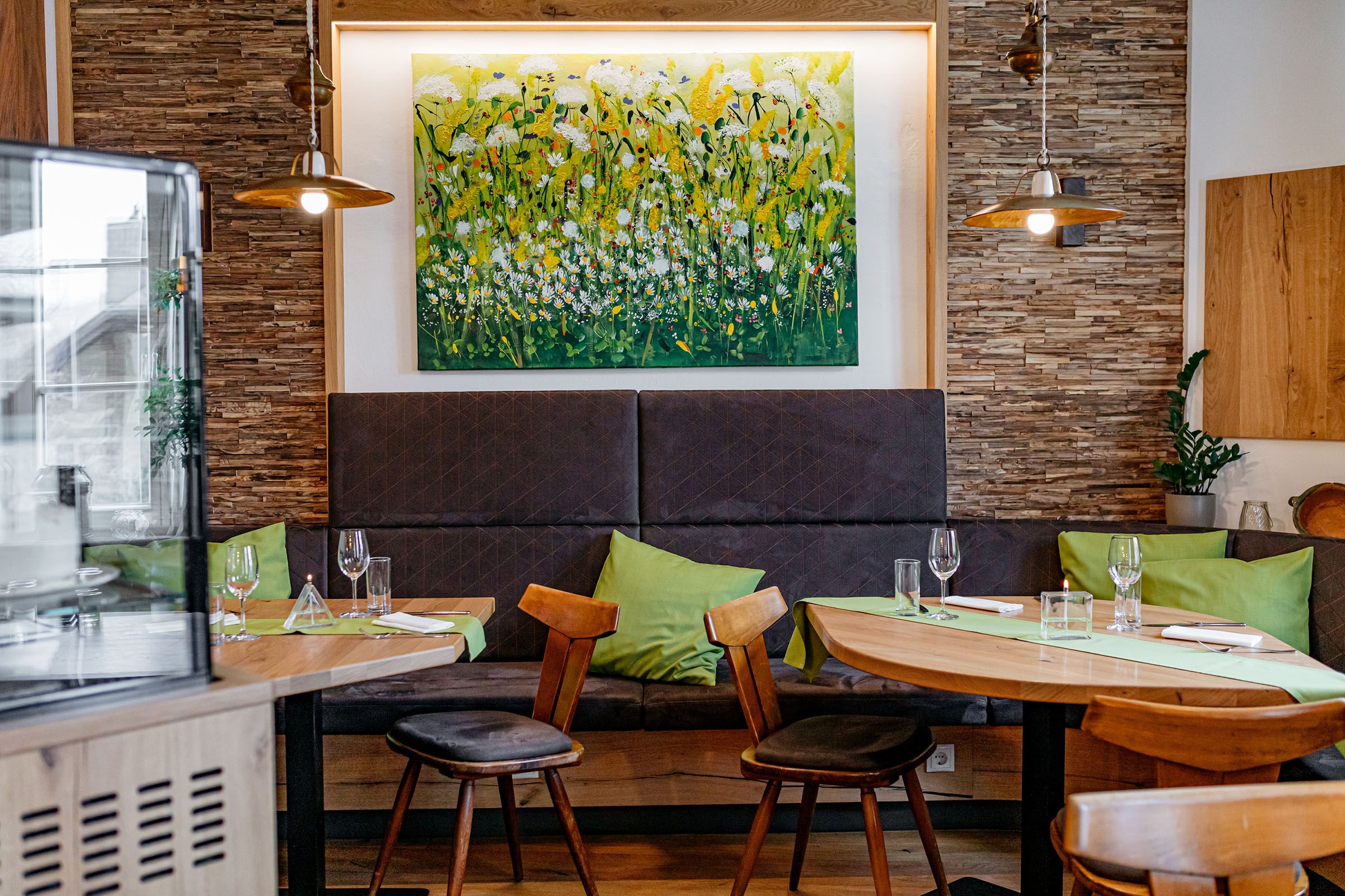 Gemütliches Gastzimmer mit Holzmöbeln, grünen Kissen und einem Blumenbild an der Wand.