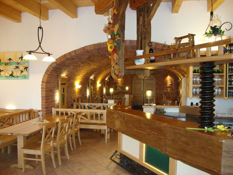 Innenansicht eines traditionellen Heurigen mit Holzmöbeln und Backsteinwänden.