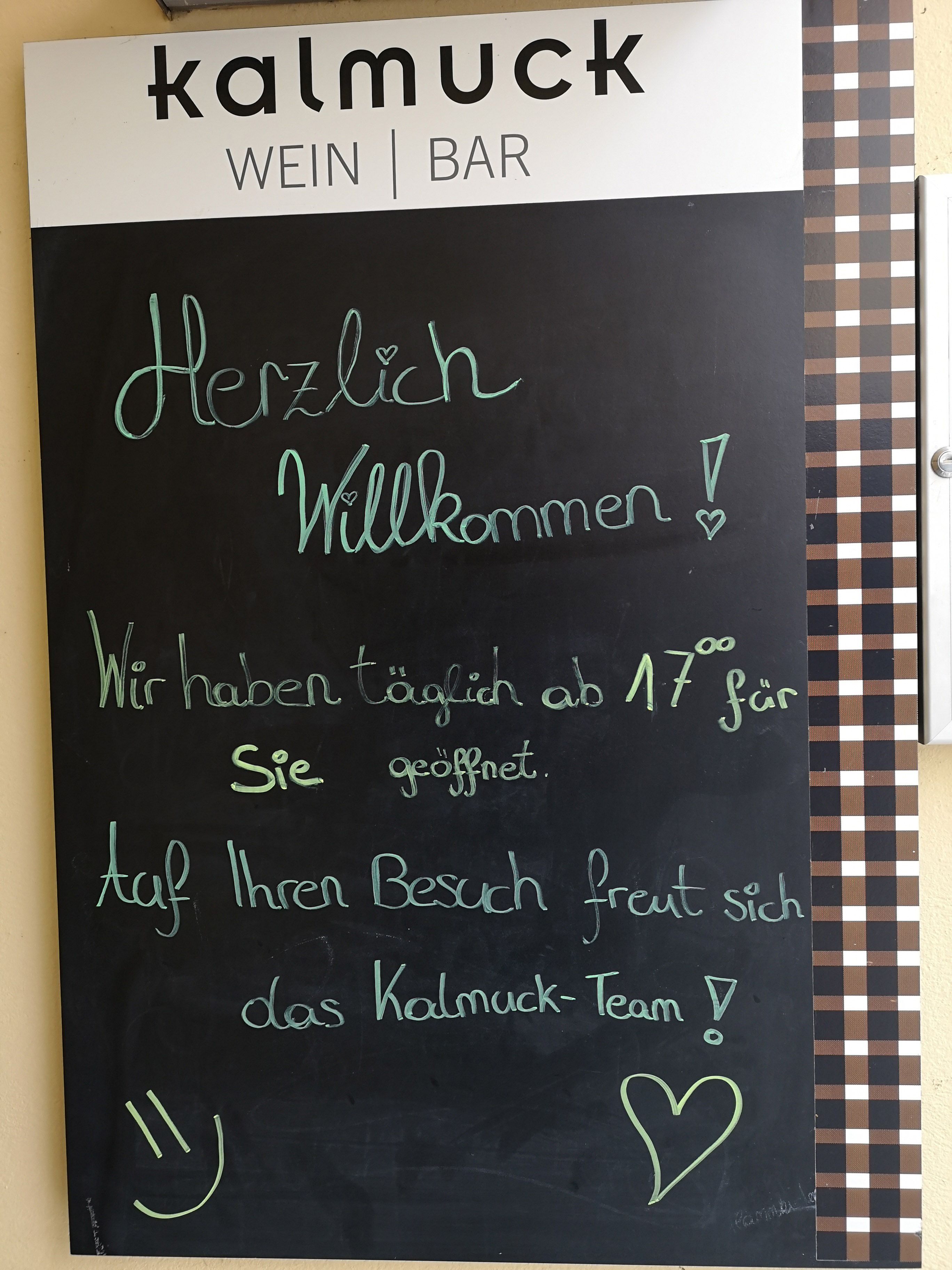 Tafel mit Begrüßungstext vor einer Weinbar namens Kalmuck.