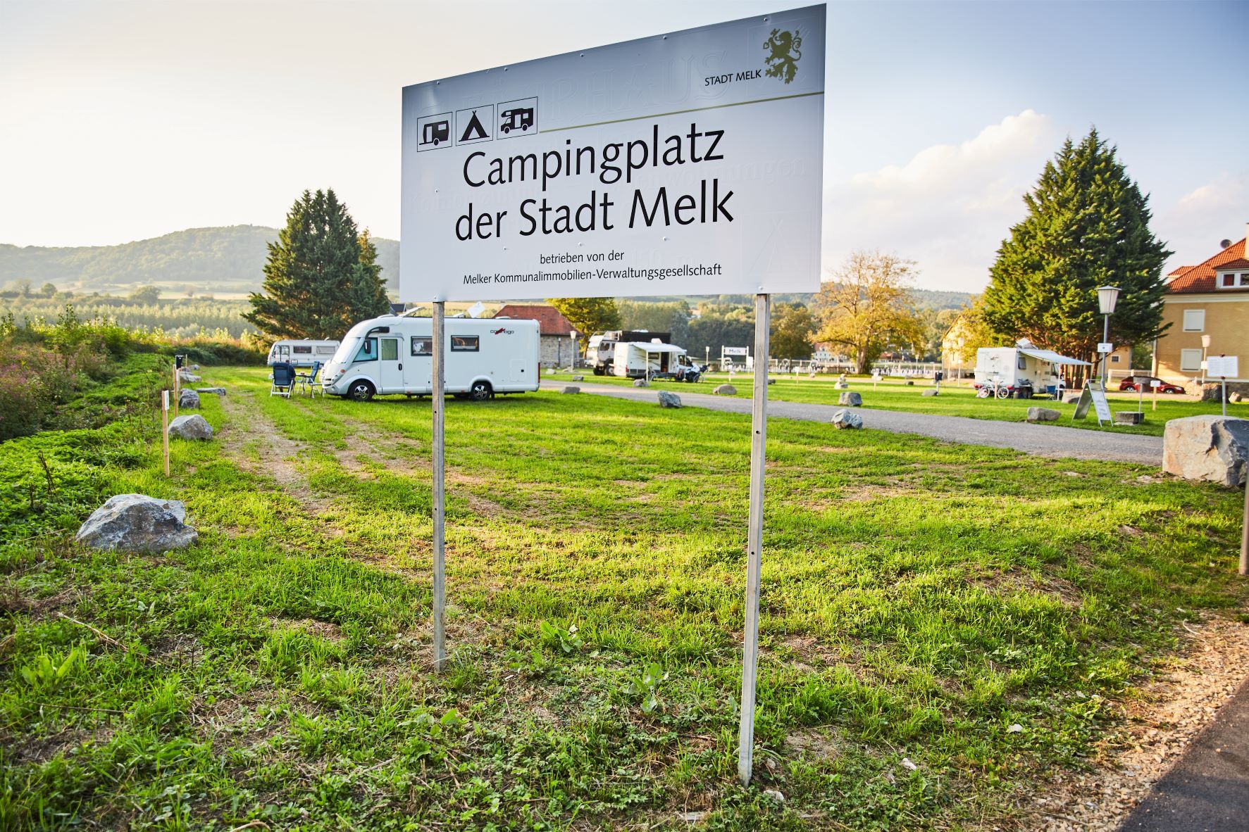 Campingplatz der Stadt Melk mit Wohnmobilen und grüner Landschaft.