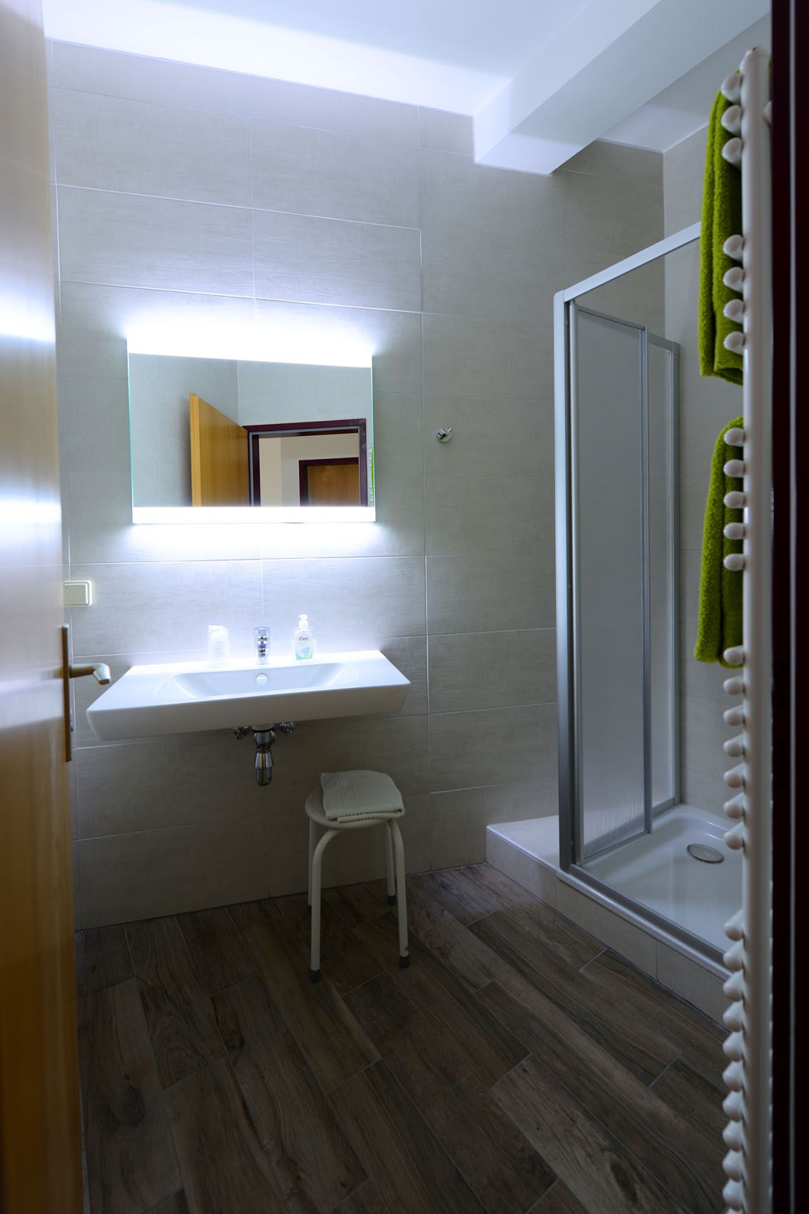 Modernes Badezimmer mit Waschbecken, beleuchteter Spiegel und Dusche.