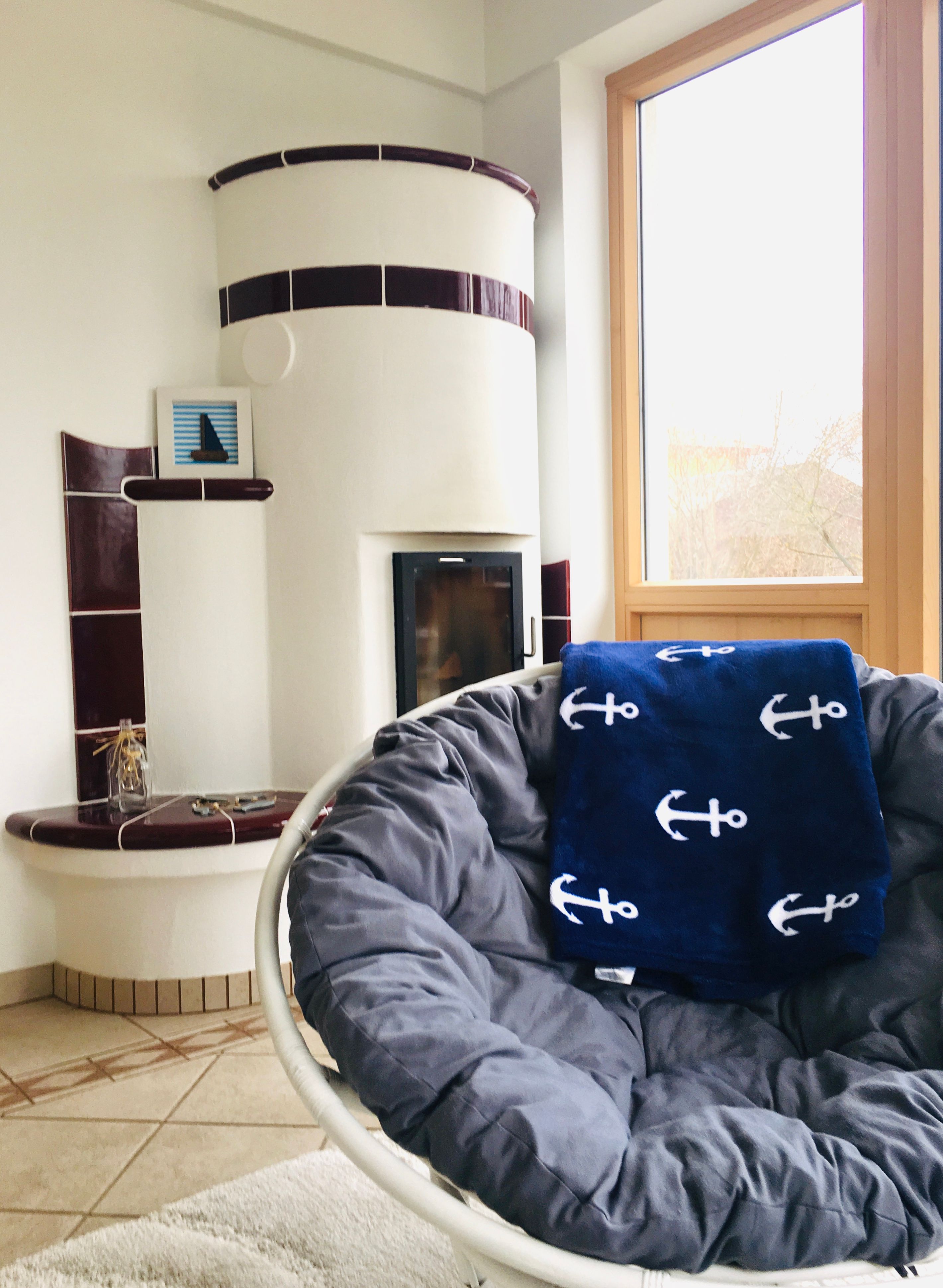 Gemütliches Wohnzimmer mit Kachelofen und Sessel.