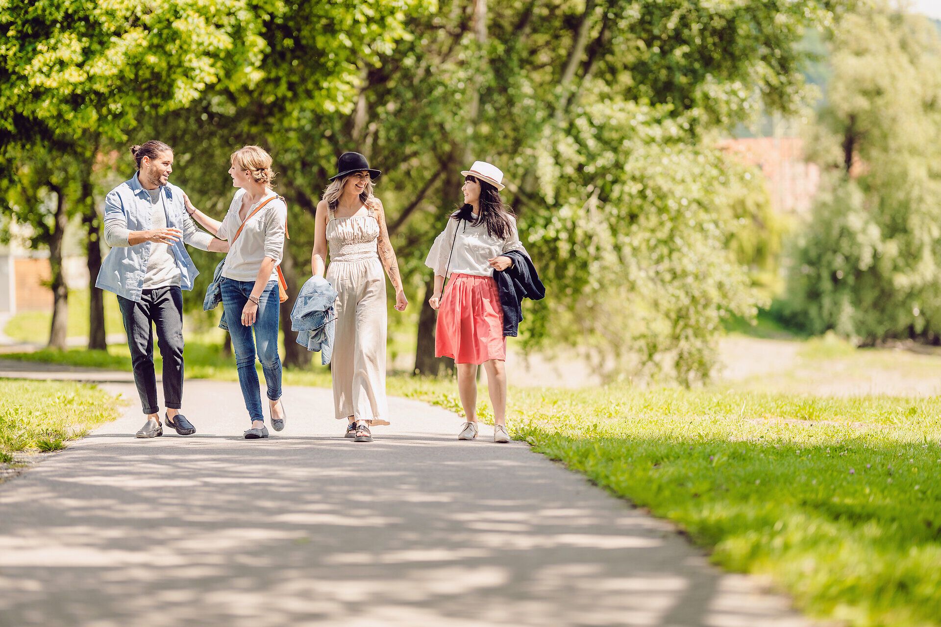 Drei Mädchen und ein junger Bursche spazieren auf dem Treppelweg entlang der Donau.
