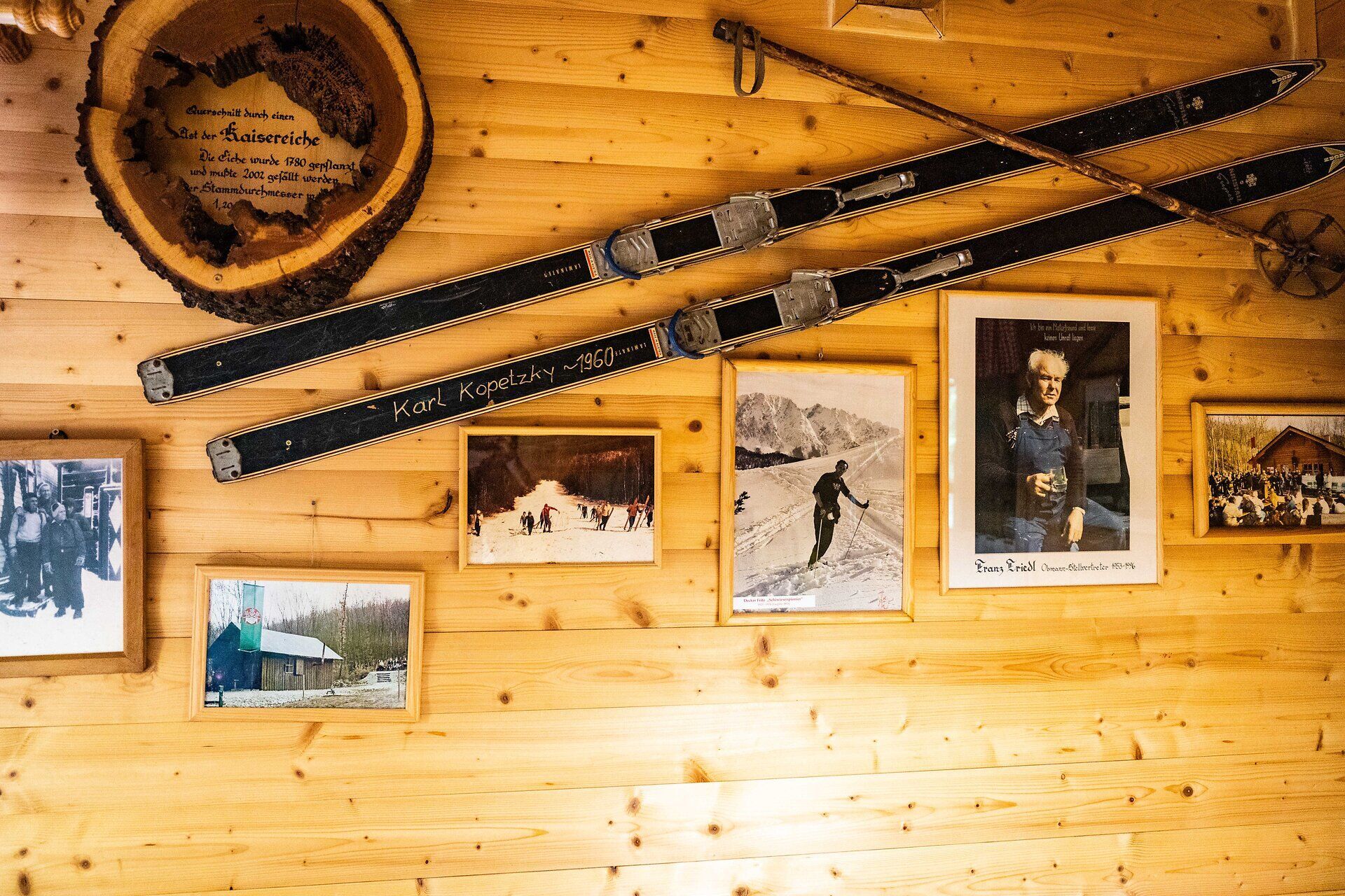 Holzwand in einer Hütte mit alten Skiern und historischen Fotografien
