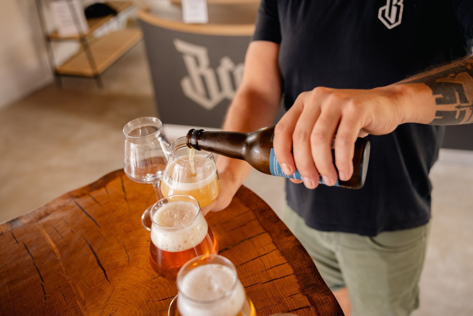 Mann schenkt Bier aus einer Flasche in ein Glas ein.