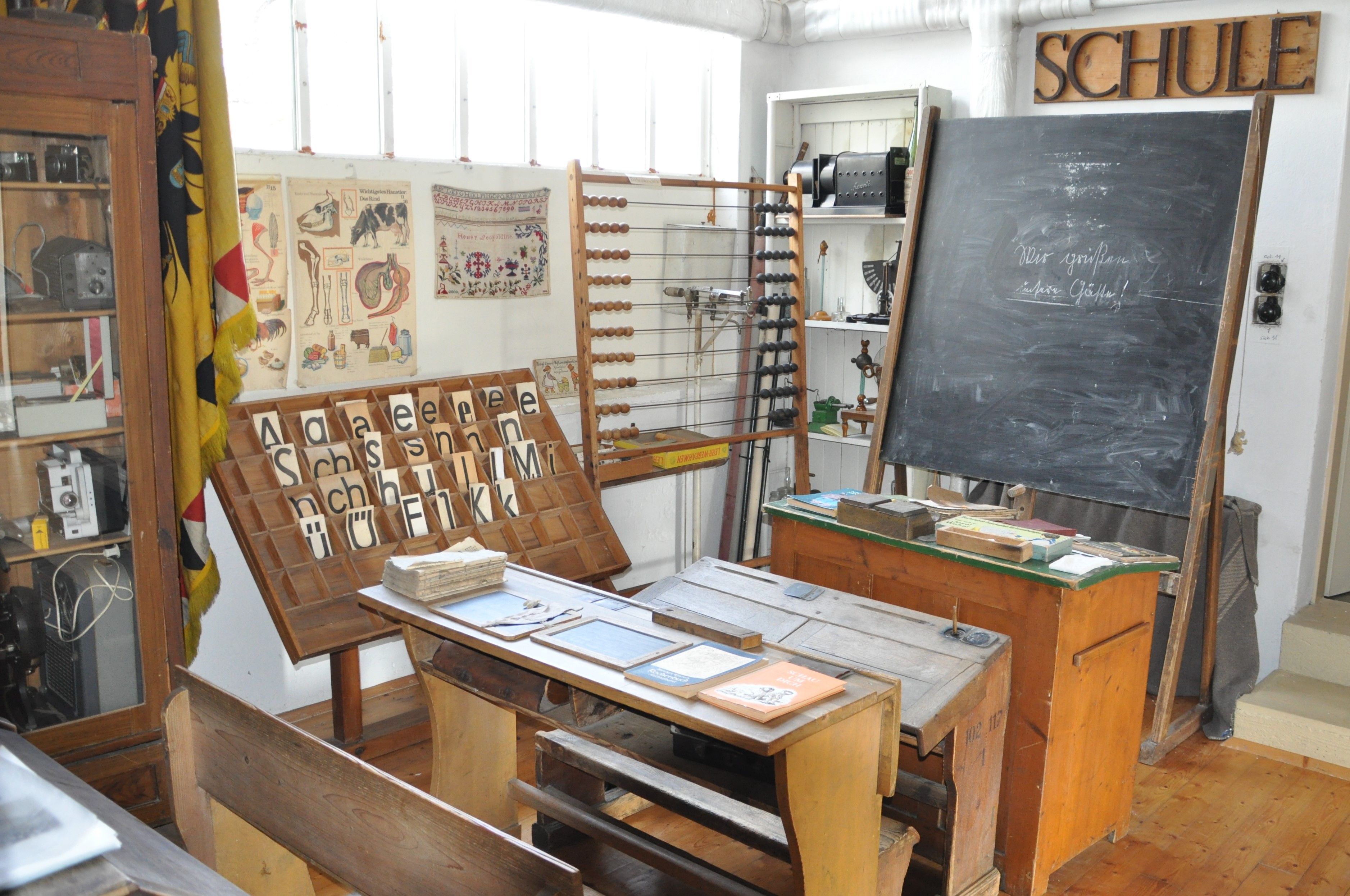 Historisches Klassenzimmer im Heimatmuseum Michelhausen mit Schultafel, Pult und Lehrmaterialien.