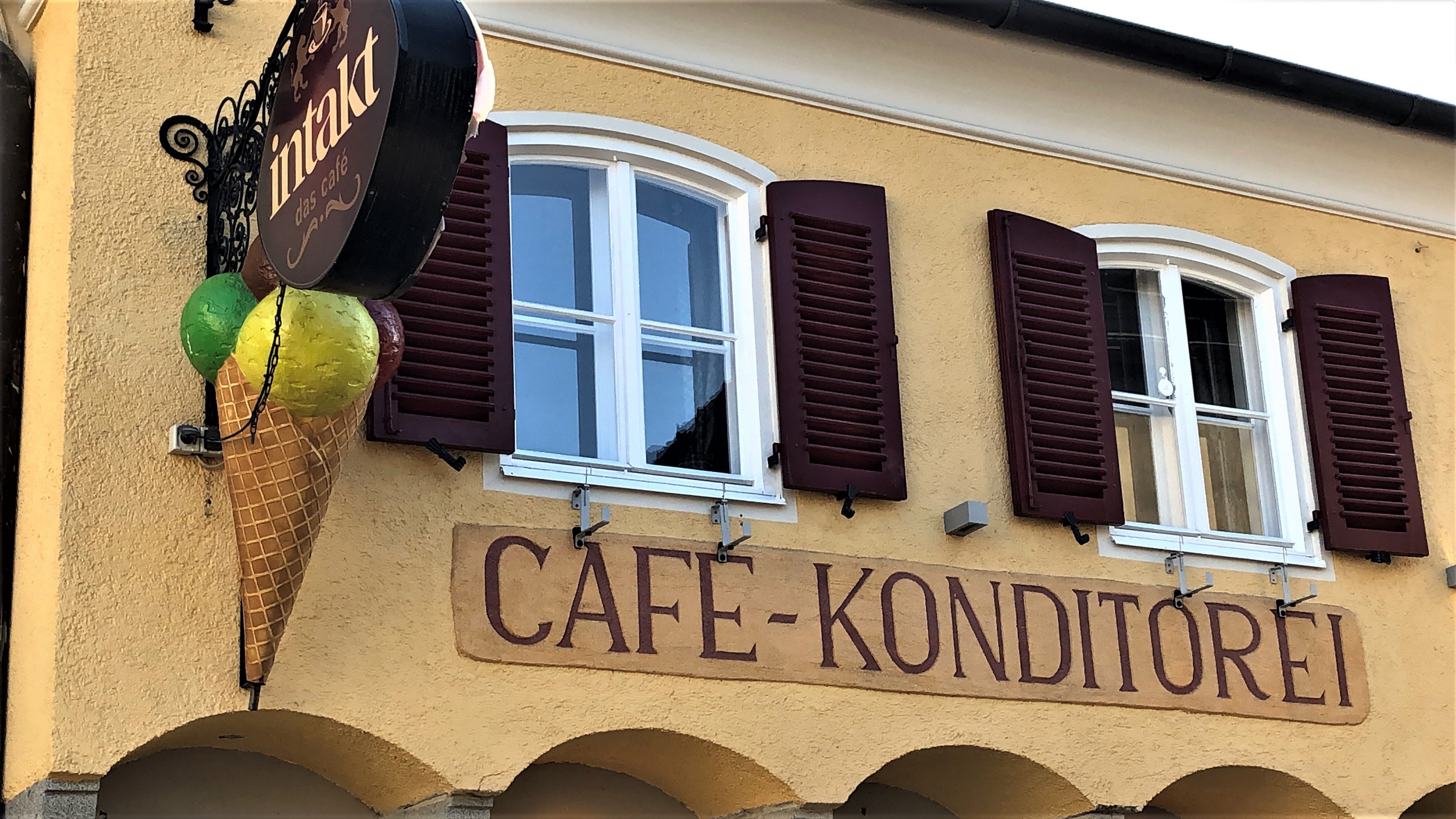 Fassade eines Cafés mit Eistüten-Dekoration und Schriftzug 'Cafe-Konditorei'.