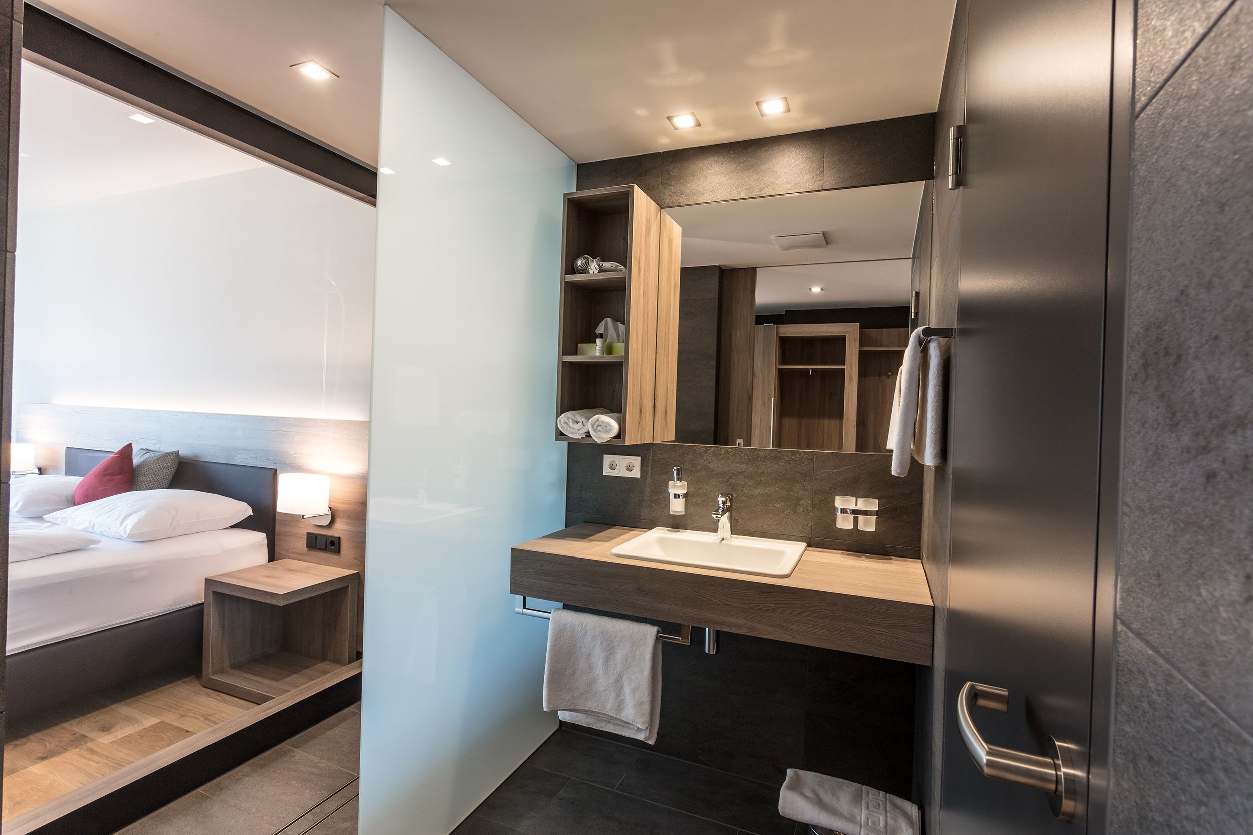 Modernes Hotelzimmer mit Bad und Doppelbett.