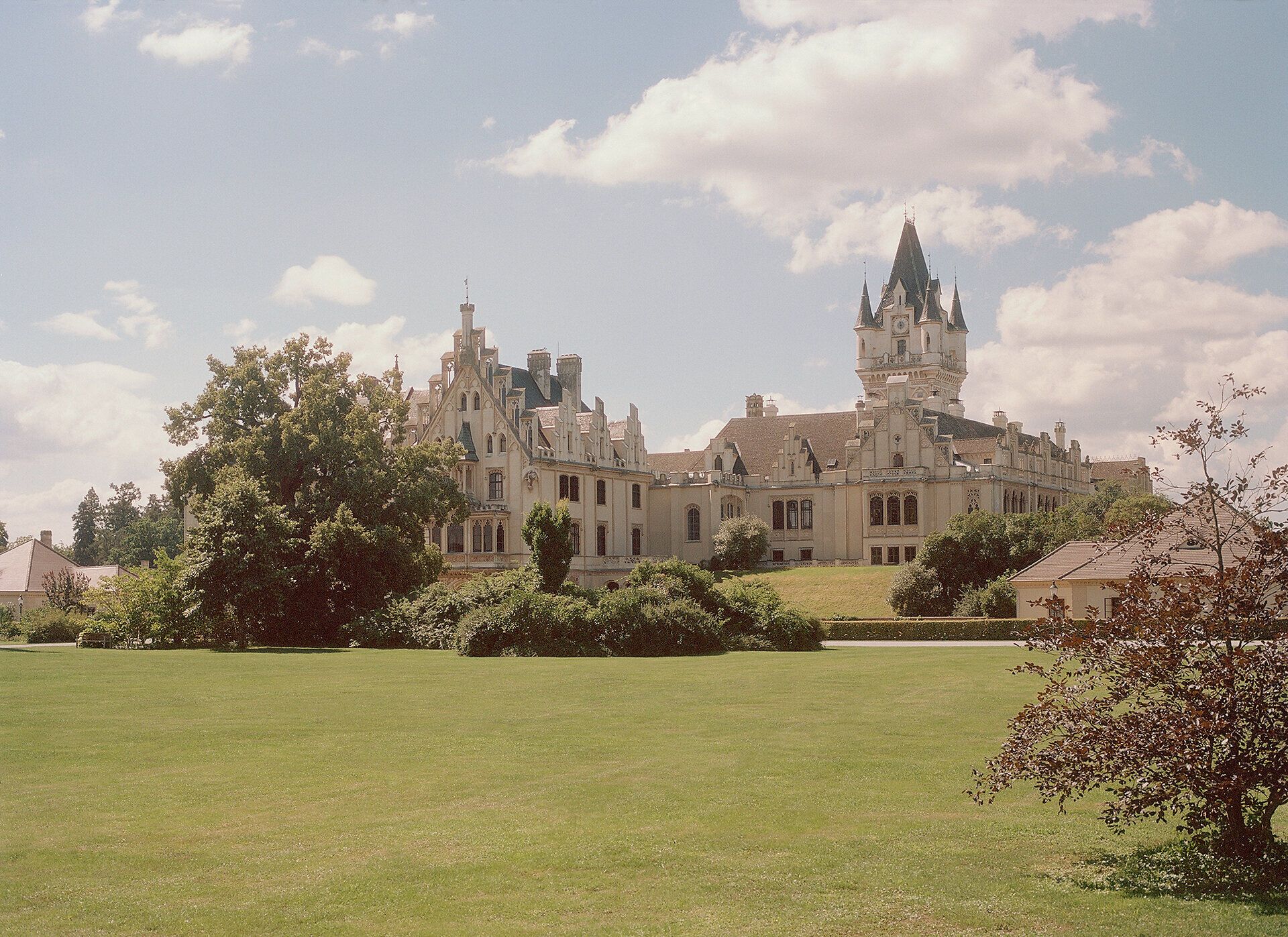 Schloss Grafenegg mit weitläufigem Rasen und Bäumen im Vordergrund.