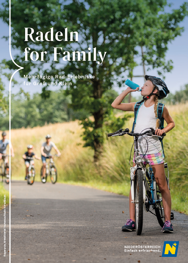 Ein Kind steht mit seinem Fahrrad auf einem Radweg und trinkt aus seiner Trinkflasche.