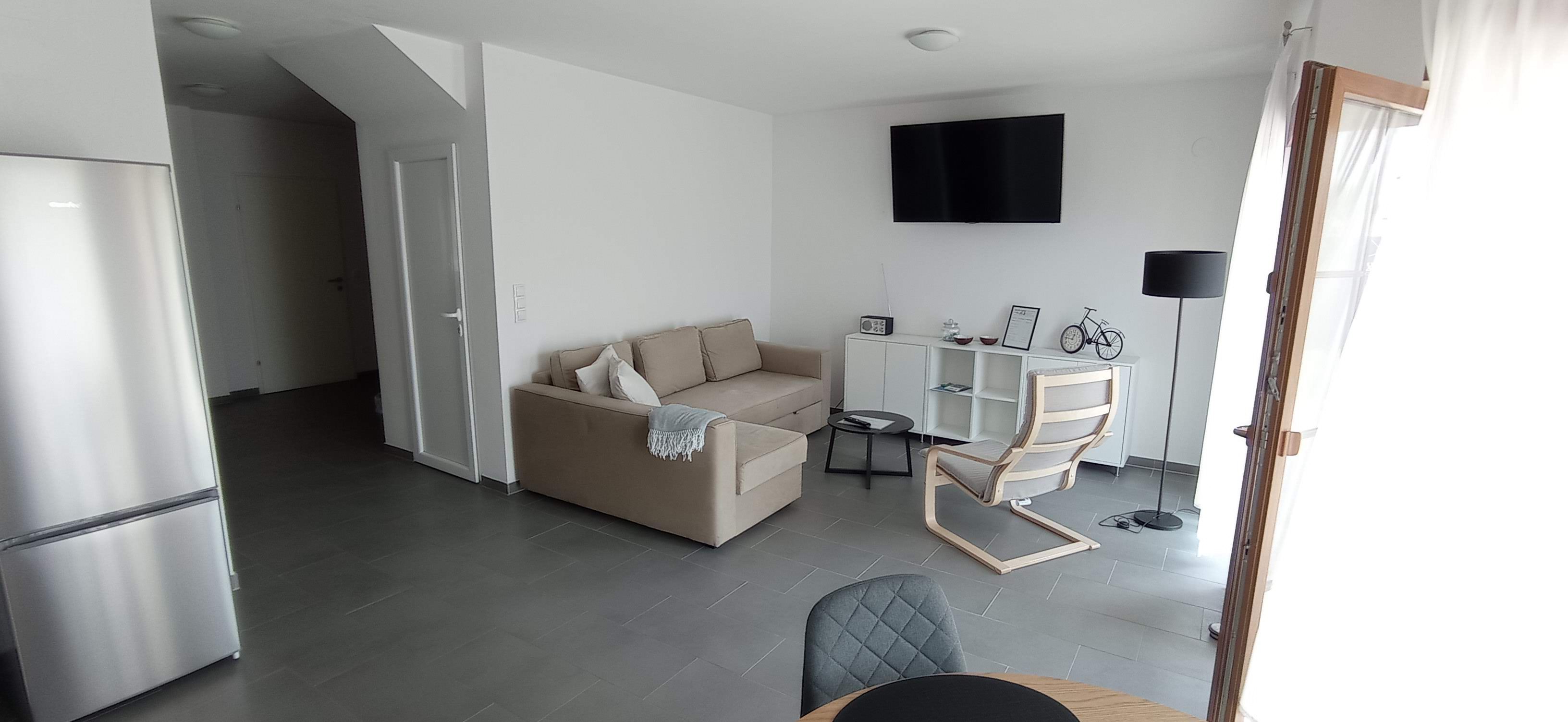 Wohnzimmer mit beiger Couch und weißen Wänden 