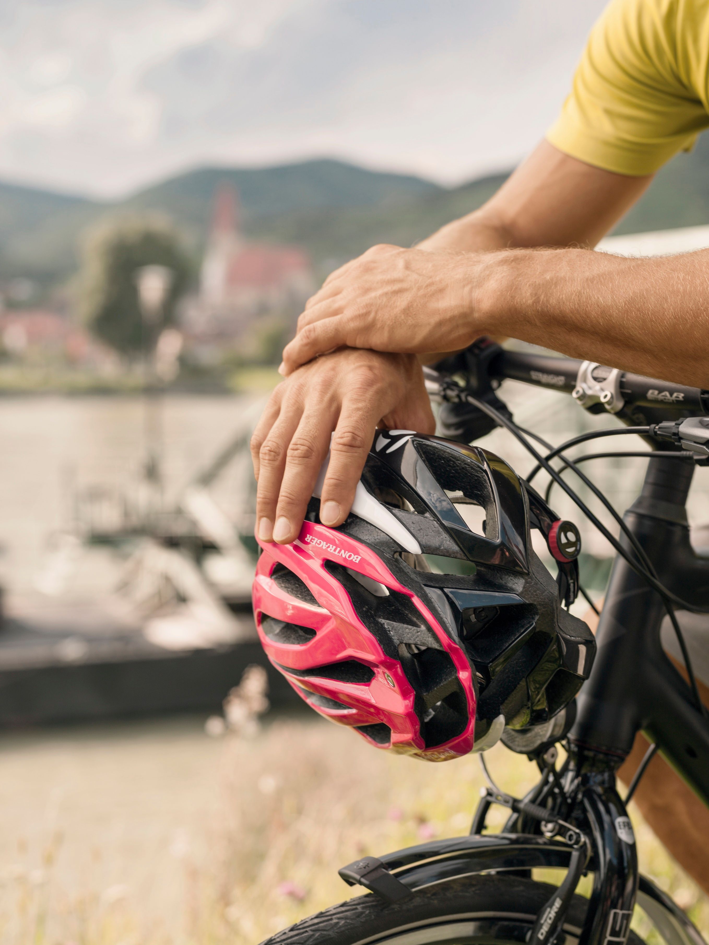 Zwei Hände halten einen Radhelm auf einem Fahrradlenker