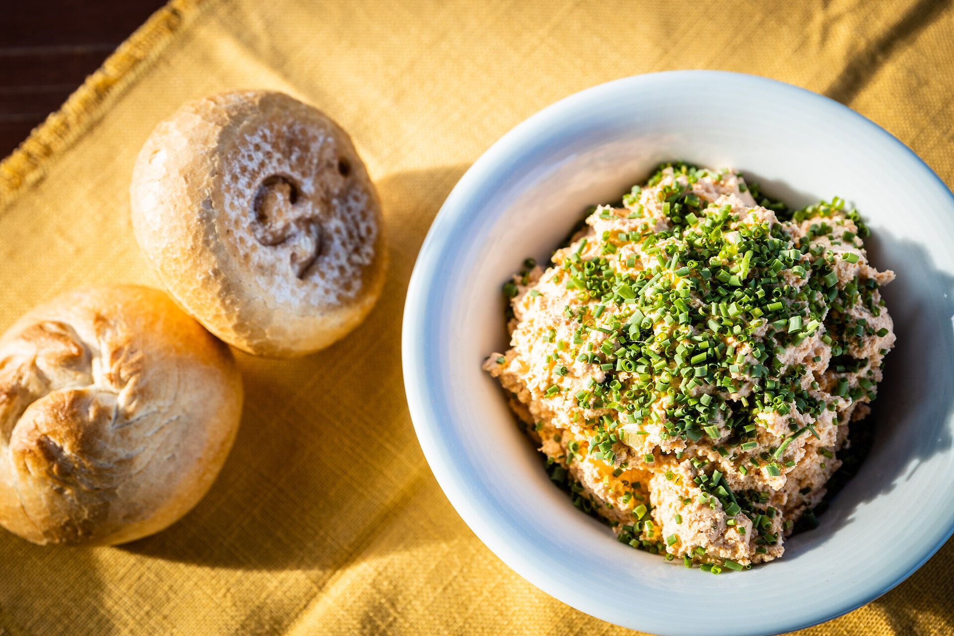 Ein köstlicher Liptauer, garniert mit frischem Schnittlauch, lädt zum Genießen ein. Dazu passen die knusprigen Laberl, die perfekt für einen geselligen Abend sind. Diese Kombination verspricht ein unvergessliches Geschmackserlebnis in einer einladenden Atmosphäre.