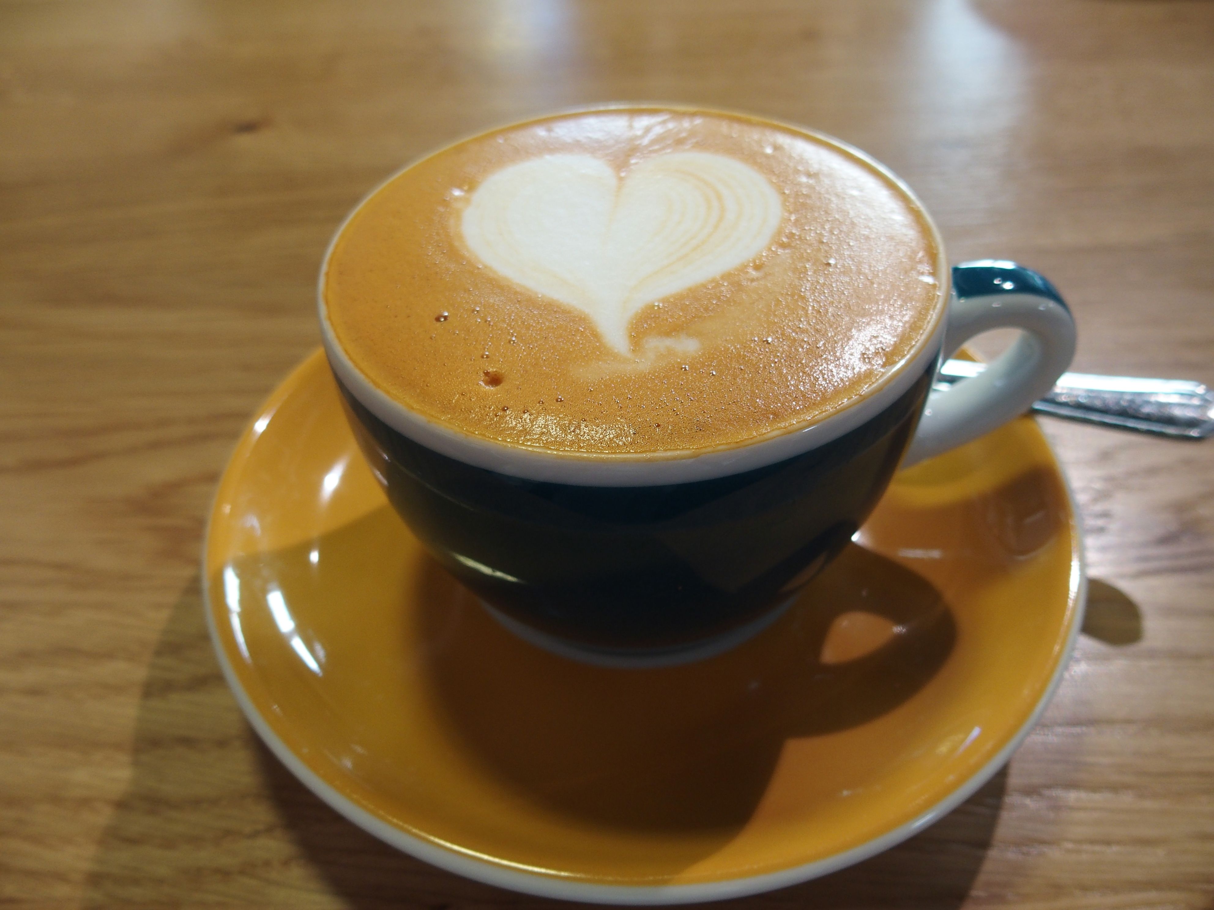 Eine Tasse Cappuccino mit Herz-Latte-Art auf einem Holztisch.