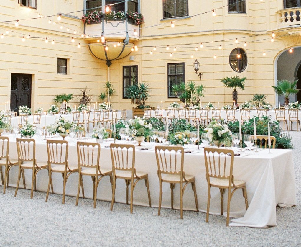 Innenhof von Schloss Eckartsau mit festlich gedeckten Tischen und Lichterketten.