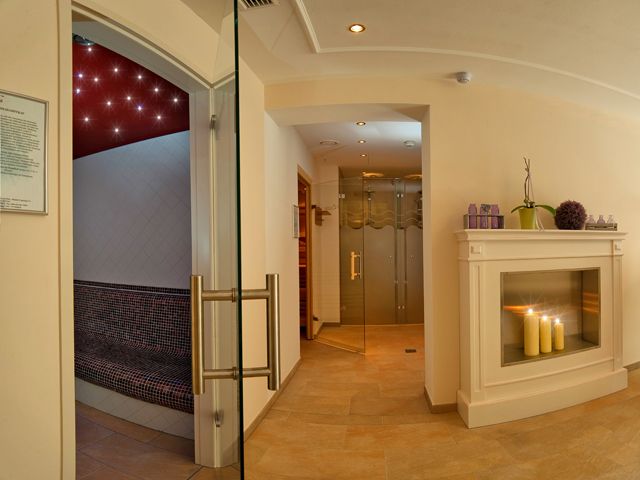 Ein eleganter Wellnessbereich mit Kamin, Kerzen und Sauna.