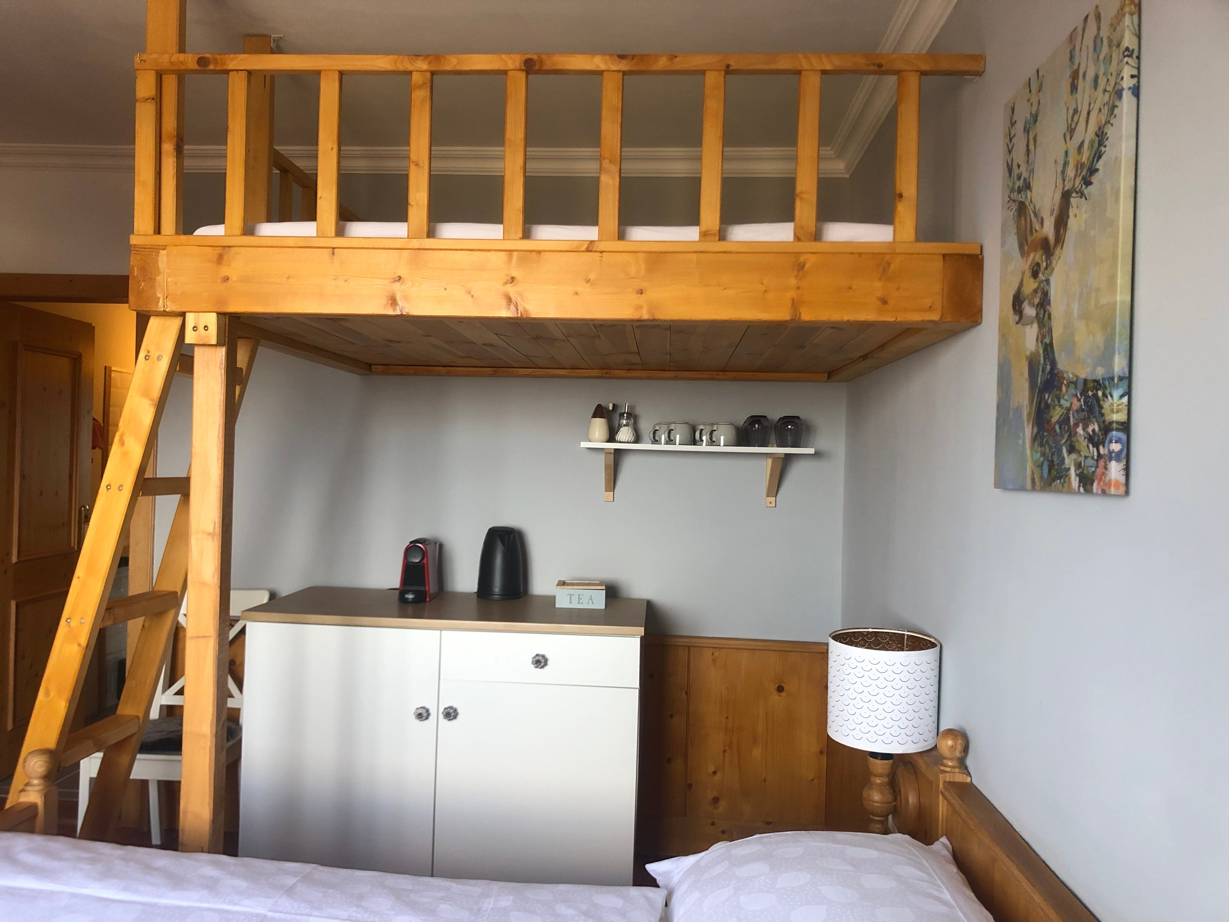 Zimmer mit Hochbett, Teestation und Hirschbild an der Wand.