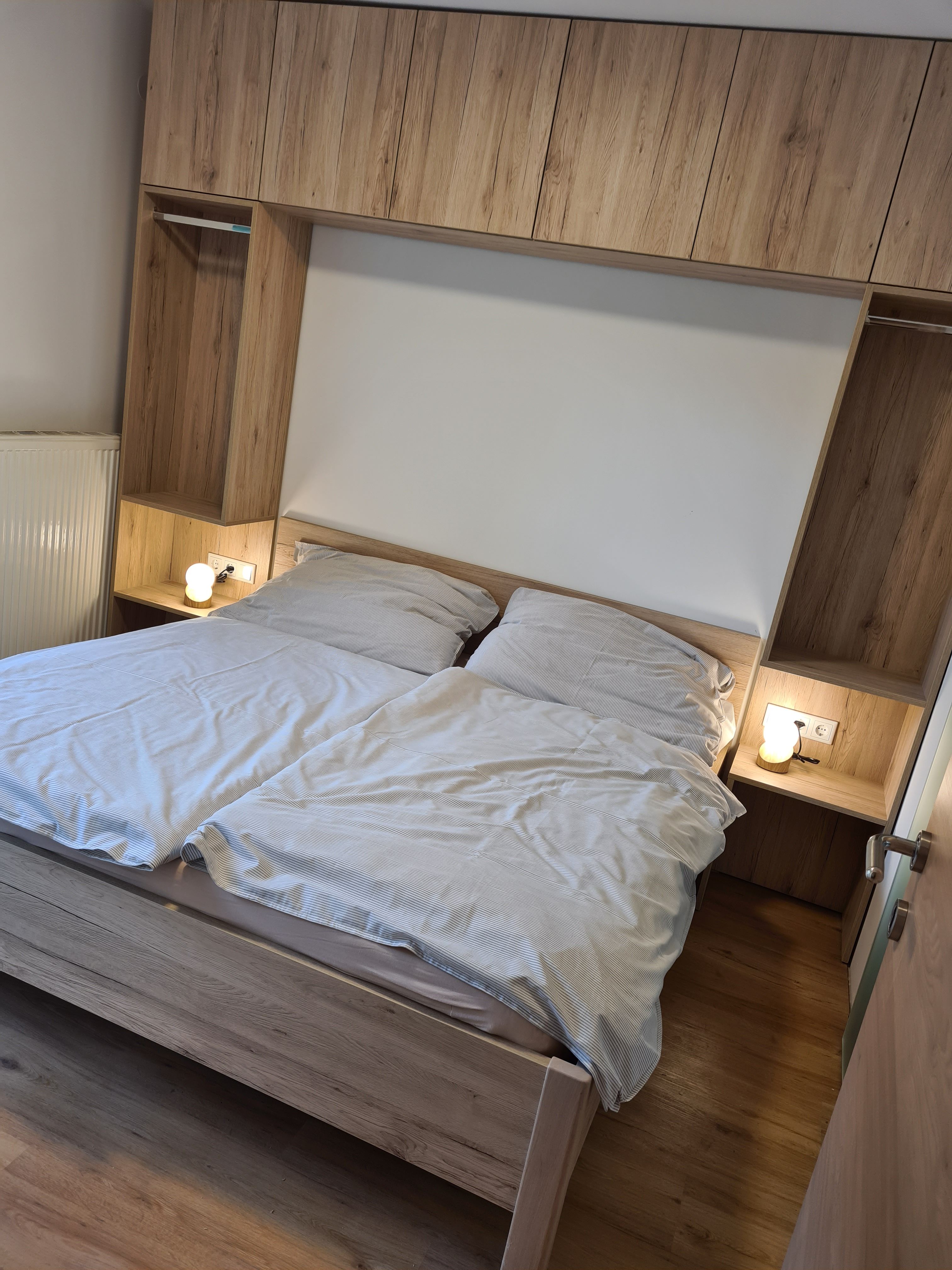 Doppelzimmer mit Holzinterieur und Doppelbett, Nachttischlampen an beiden Seiten.
