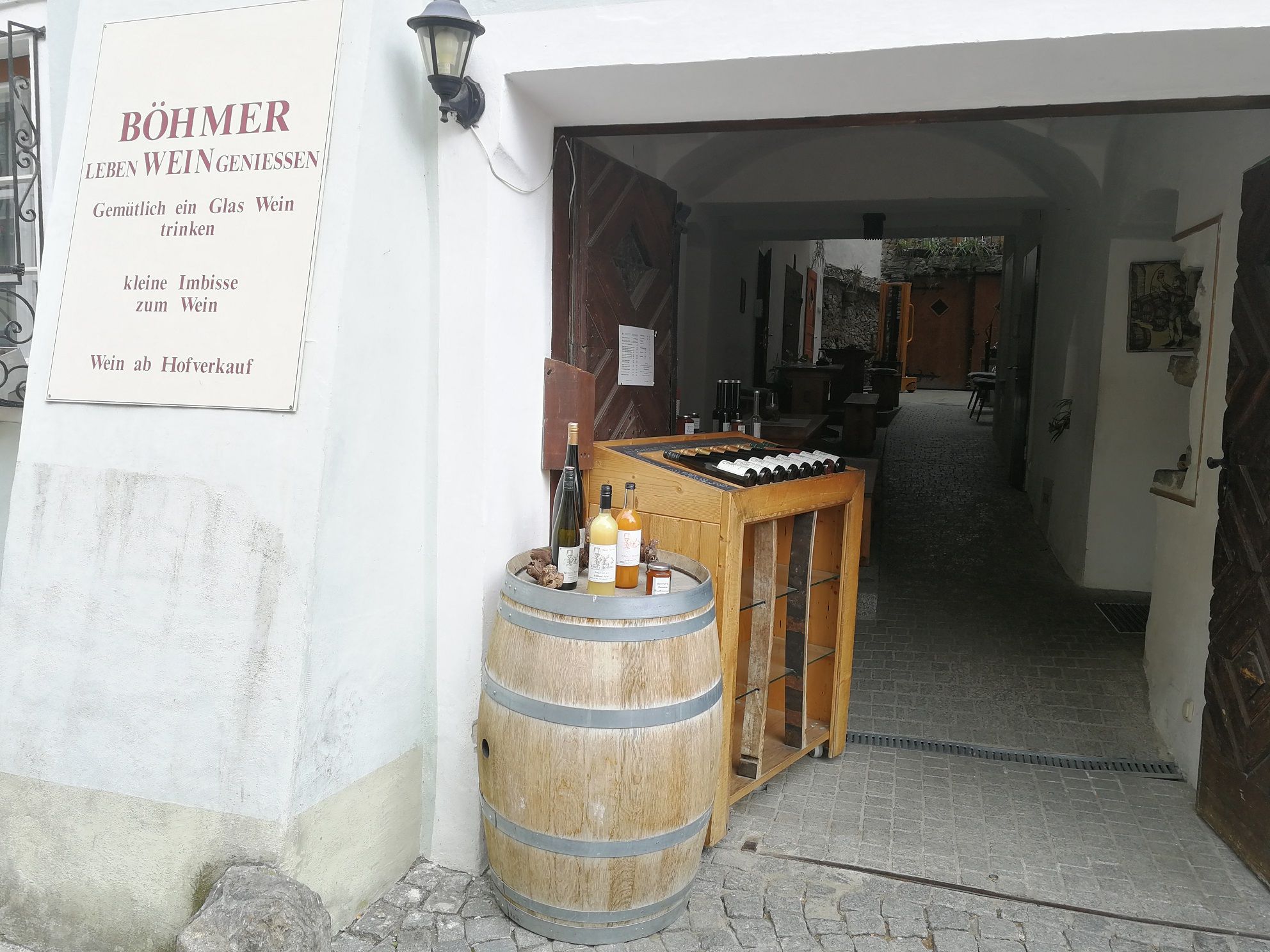 Eingang eines Weinguts mit Weinfass und Flaschen.