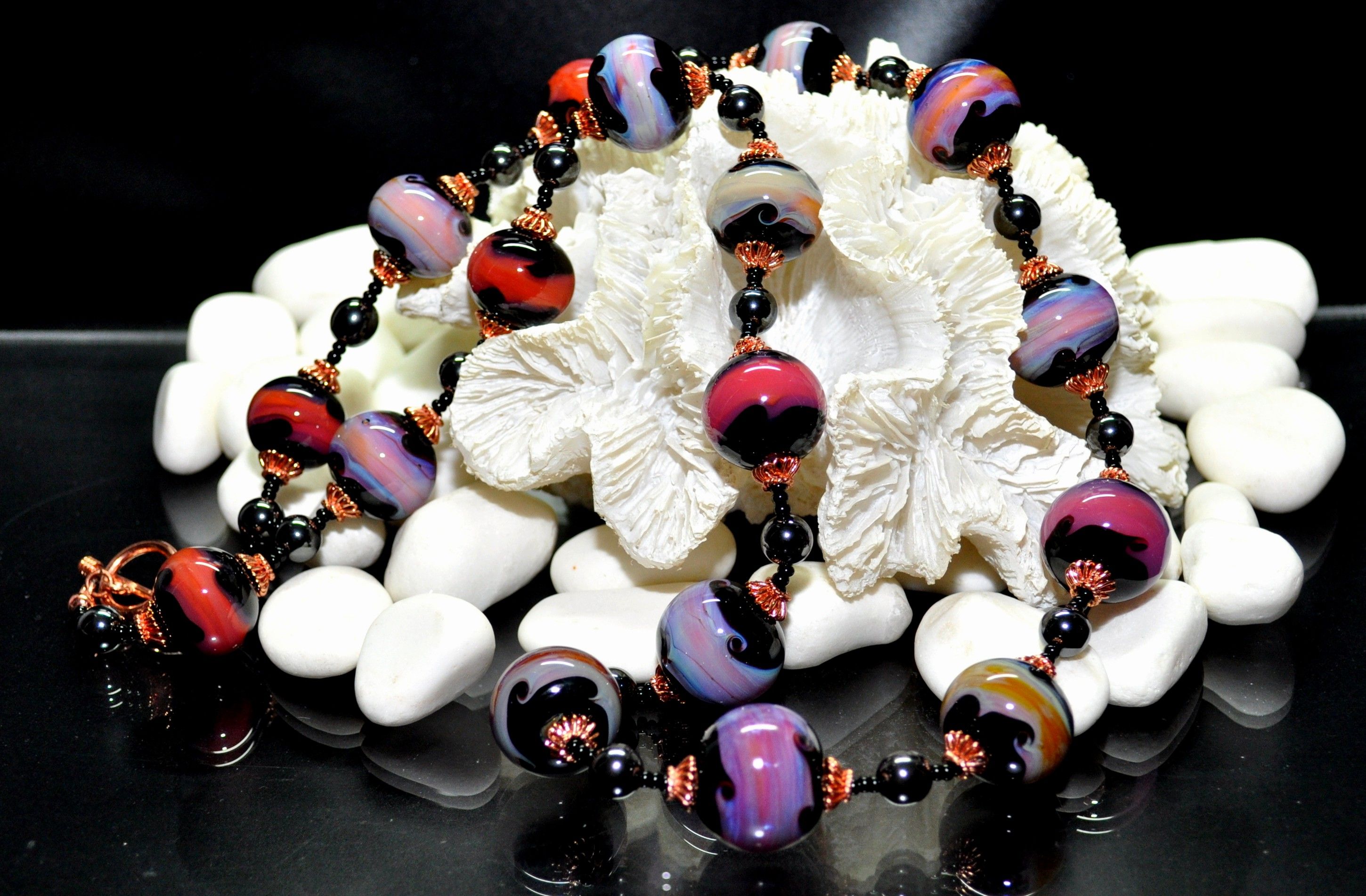 Bunte Perlenkette auf weißen Steinen und Muschel.