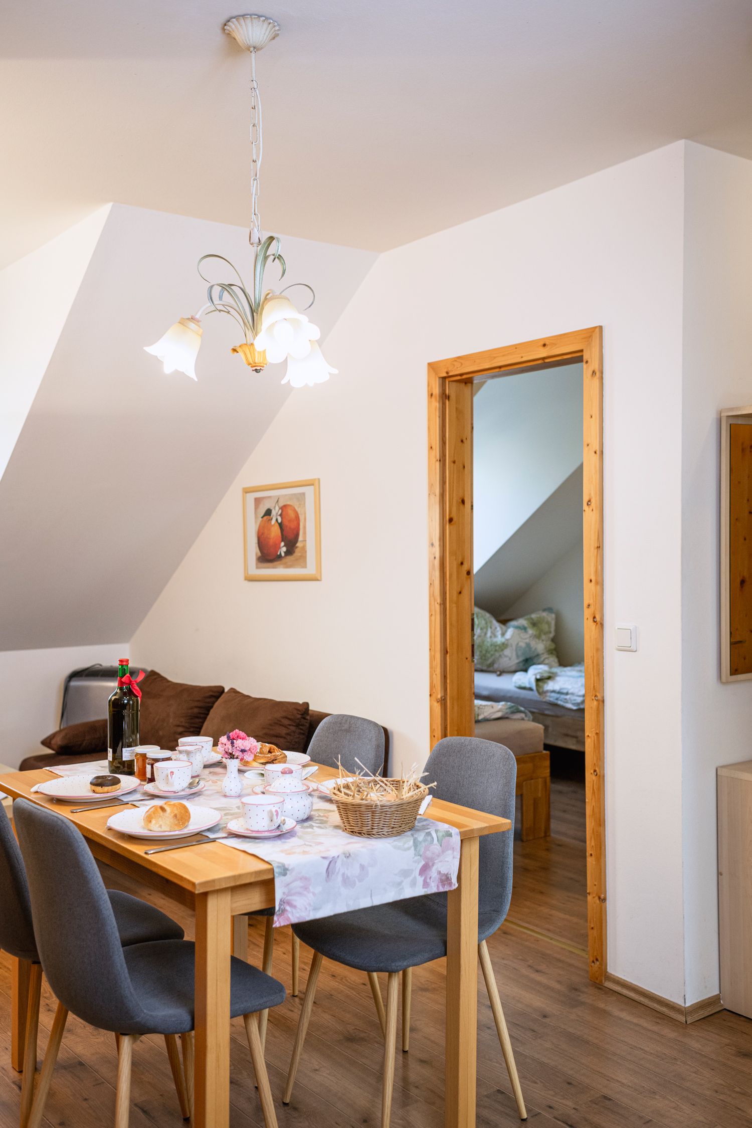Essbereich in einer Ferienwohnung mit gedecktem Tisch und Blick ins Schlafzimmer.