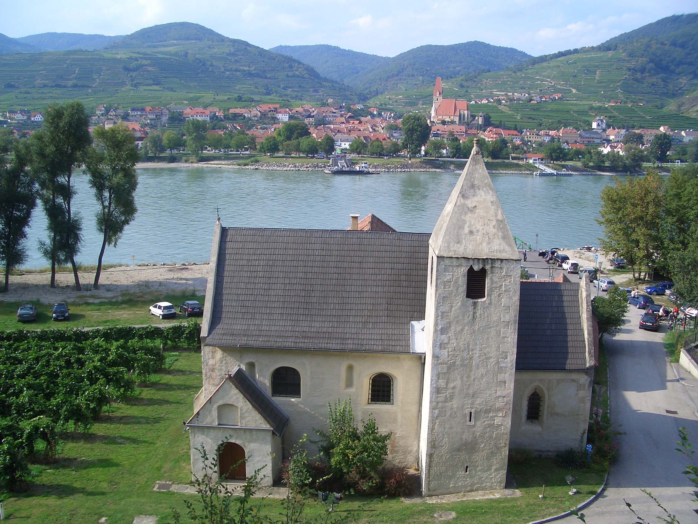 Kirche St. Lorenz mit Fluss und Dorf im Hintergrund.