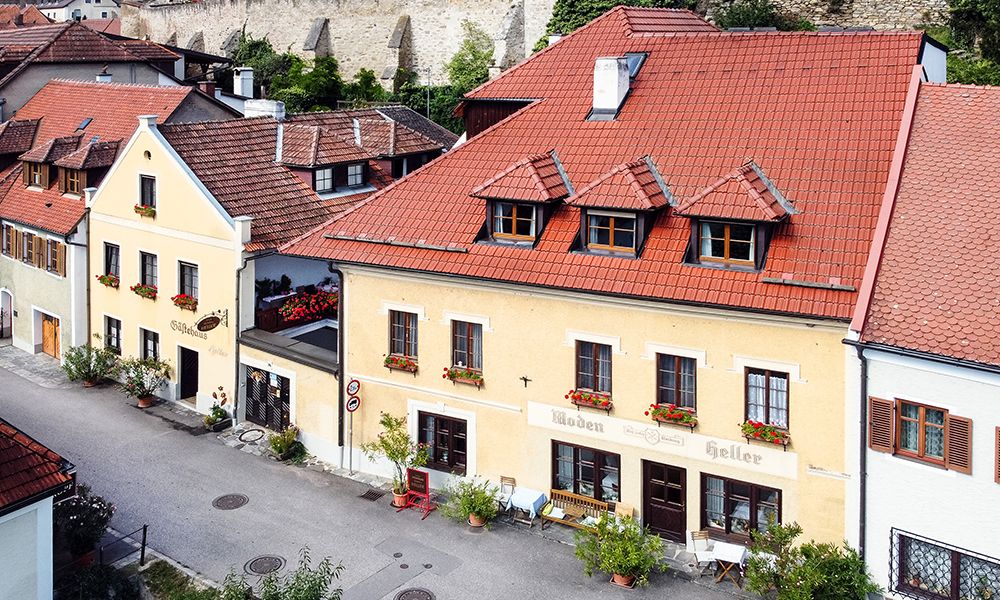 Ein traditionelles Gästehaus mit gelber Fassade und roten Dächern in einer ruhigen Straße.