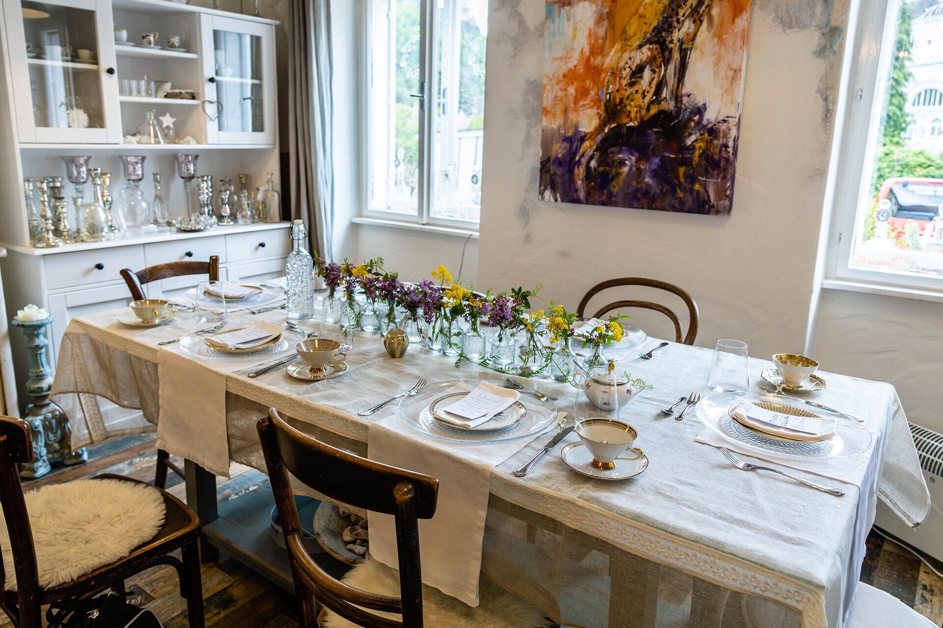 Ein schön gedeckter Tisch mit einer Zeile Blumenvasen in der Mitte.