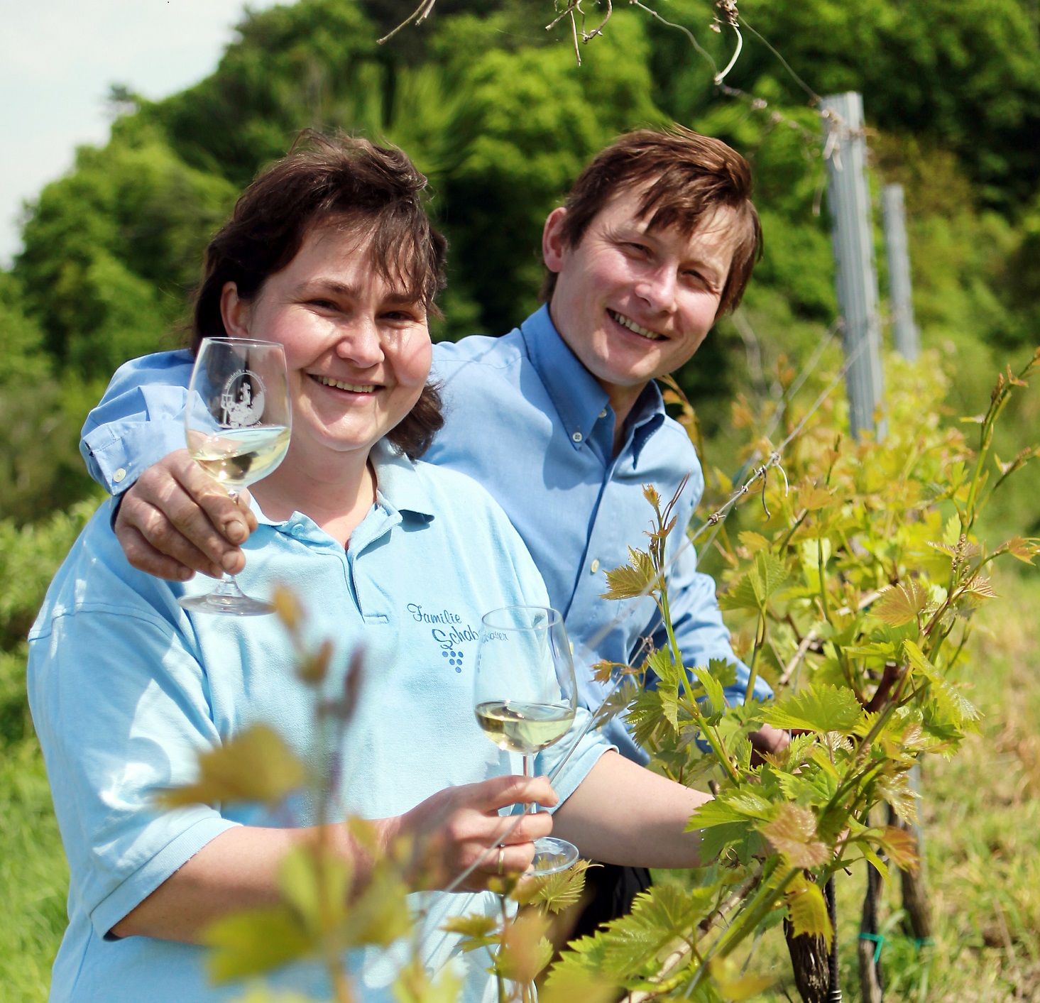Zwei Personen in einem Weinberg mit Weingläsern.
