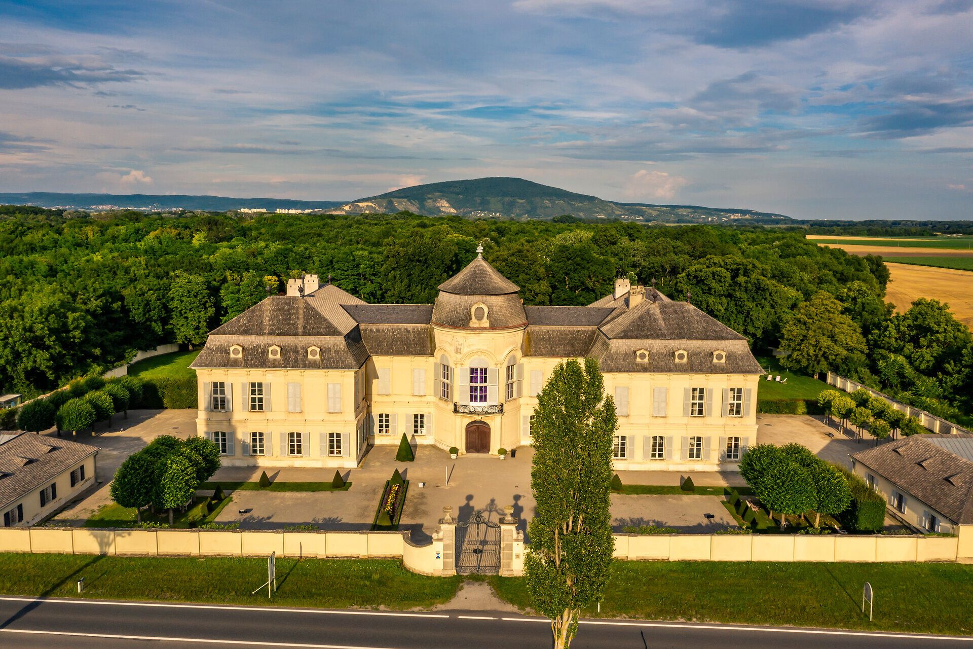 Umgeben von üppigem Grün und sanften Hügeln strahlt das Schloss Niederweiden im warmen Licht des Sommertages eine einladende Ruhe aus. Die harmonische Architektur und die gepflegten Gärten laden dazu ein, die Seele baumeln zu lassen und die Schönheit der Natur zu genießen.