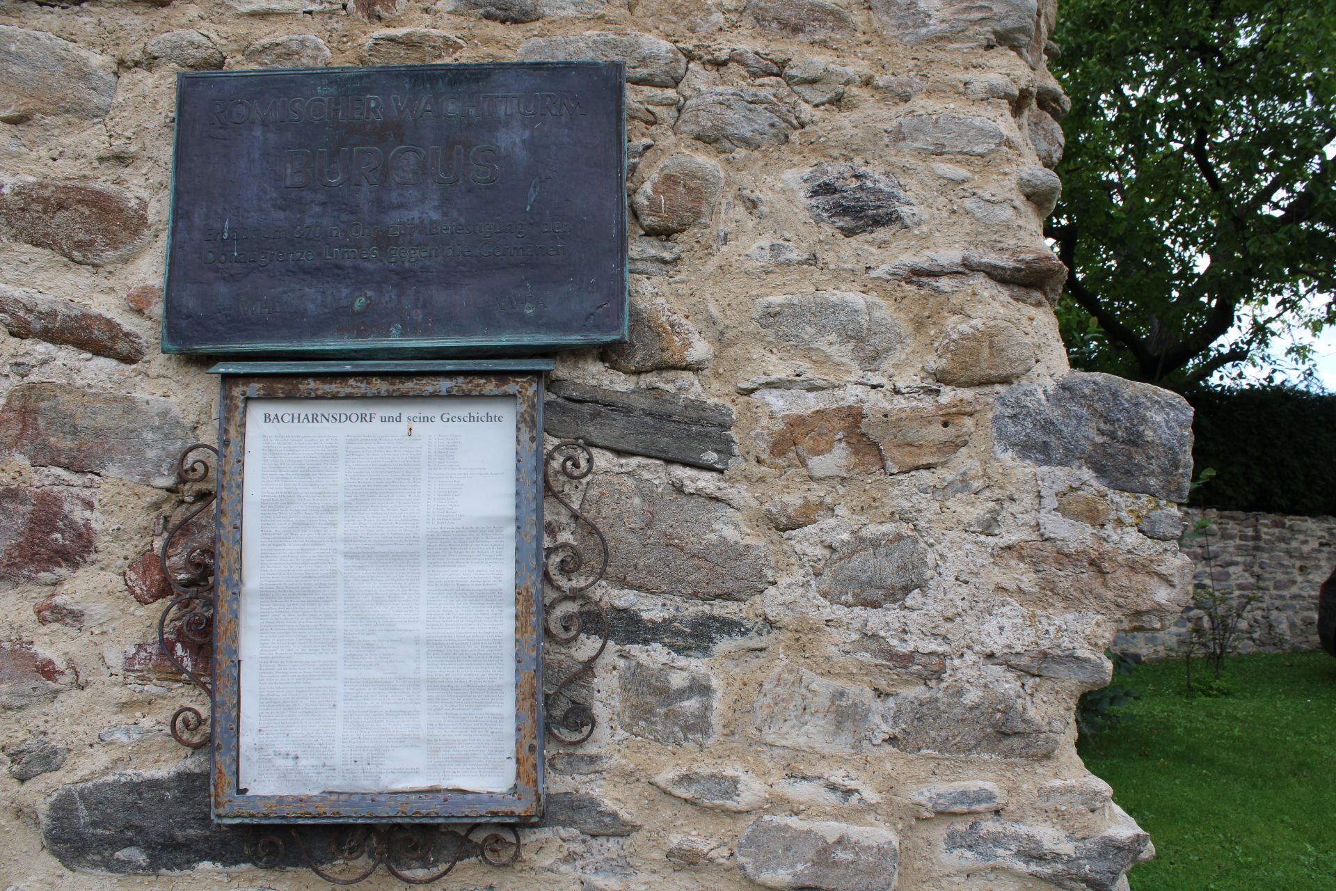 Steinmauer mit Informationstafel über den römischen Wachturm Burgus in Bacharnsdorf.