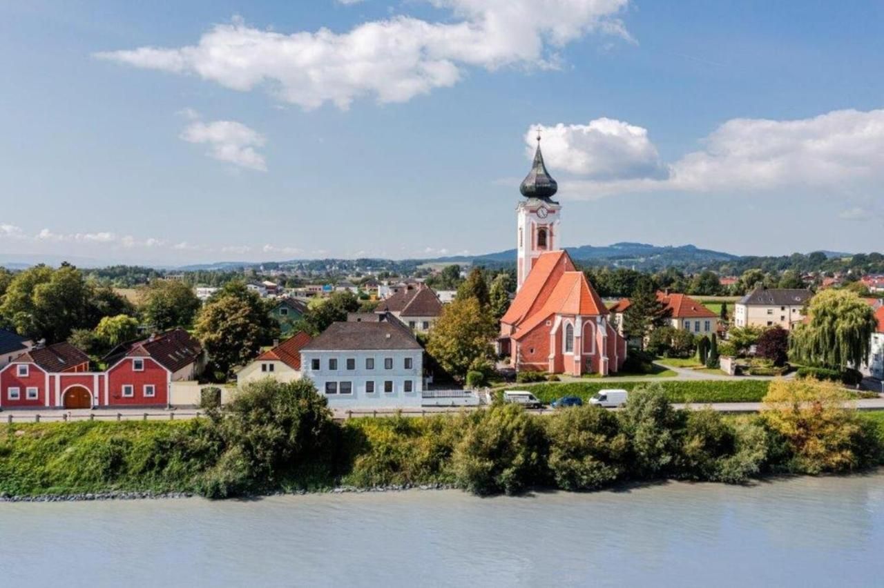 Landschaftsansicht von Persenbeug-Gottsdorf mit Kirche und Fluss im Vordergrund.