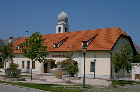 Gemeindeamt in Göttlesbrunn-Arbesthal mit rotem Dach und Turm.