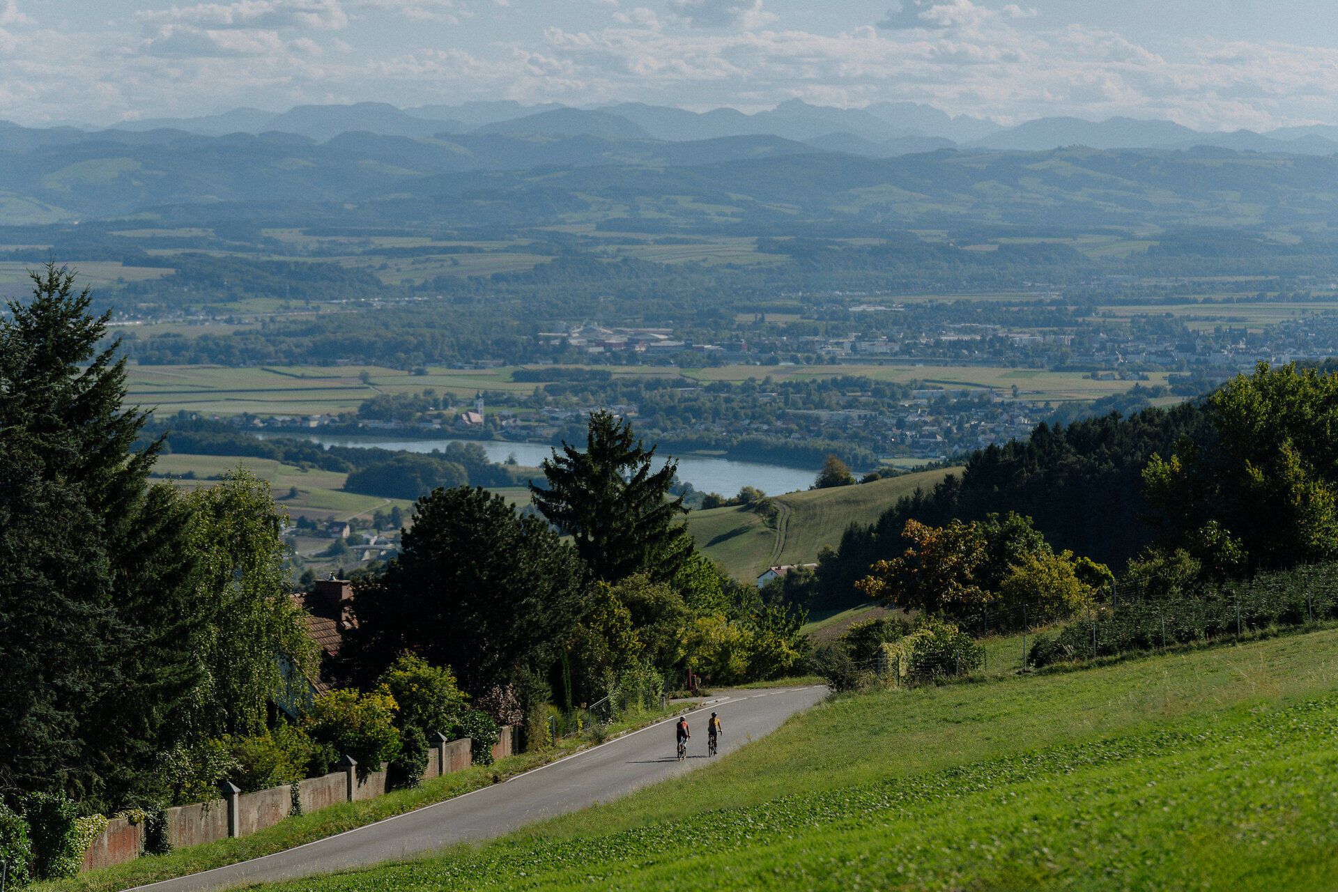 Blick auf die Donau und den Nibelungengau sowie Alpenvorland mit 2 Radfahren im Vordergrund