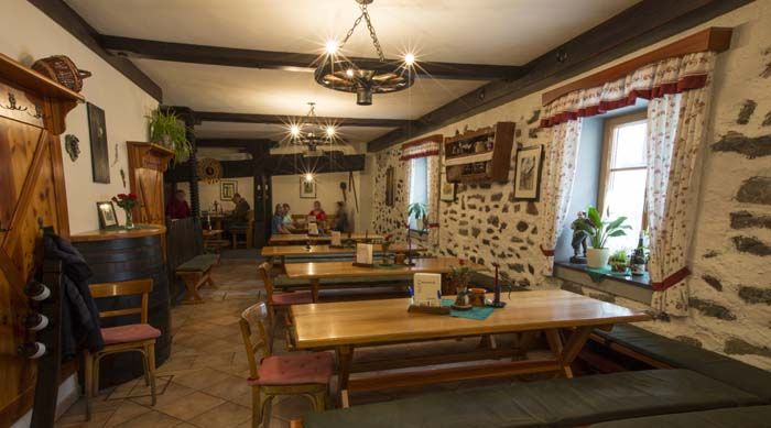 Gemütlicher Gastraum mit Holztischen und Steinwänden.