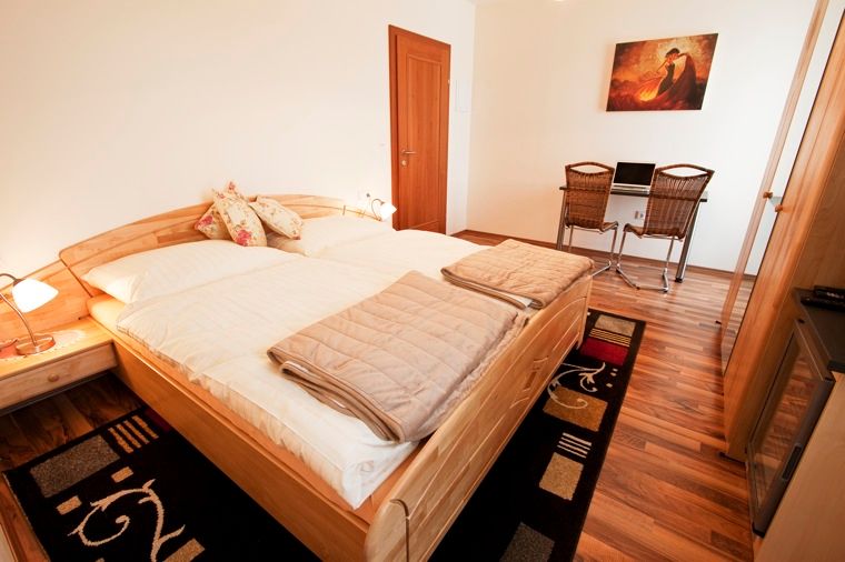 Ein gemütliches Doppelzimmer mit Holzboden, Doppelbett, Schreibtisch und Stühlen.