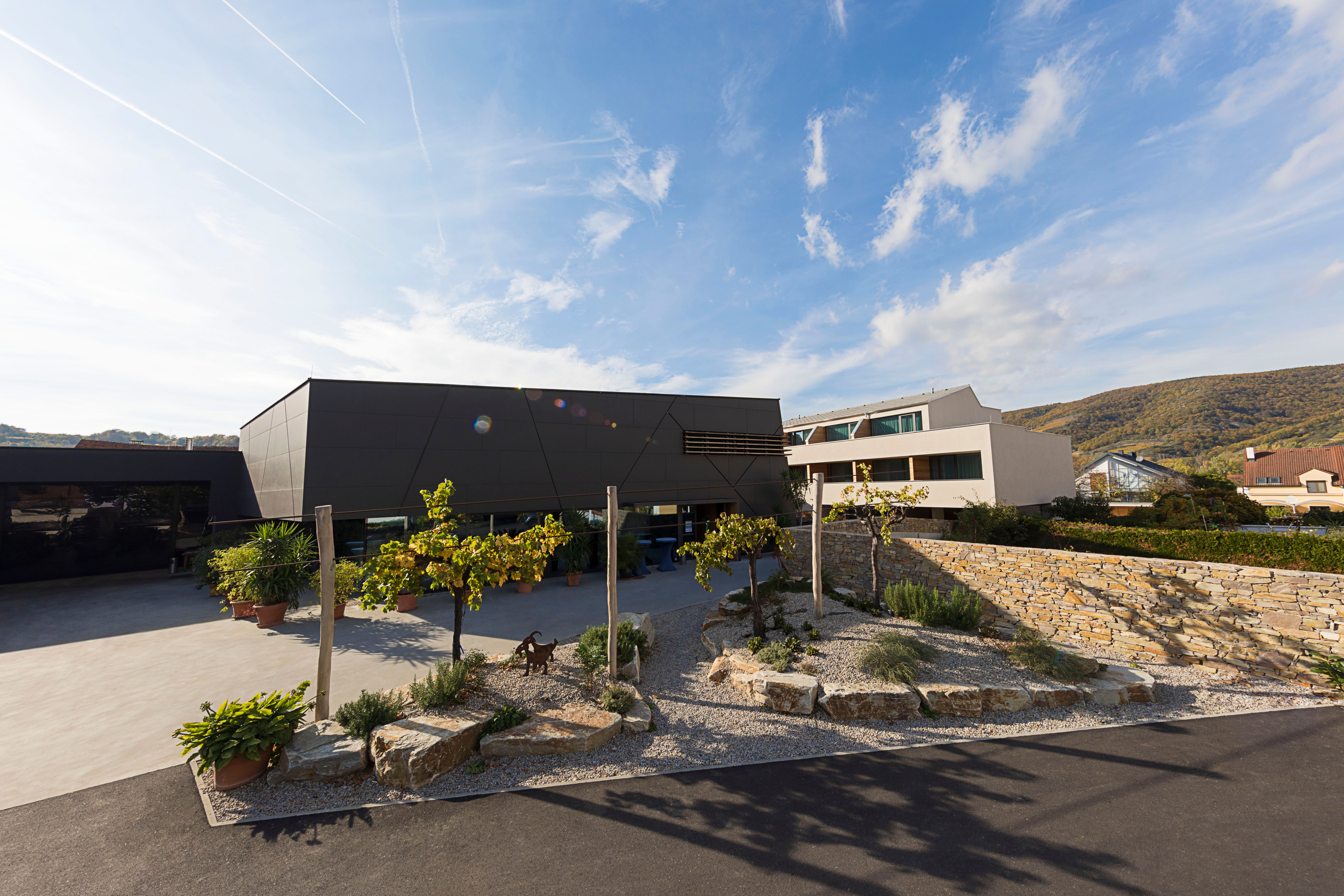 Modernes Gebäude mit Garten und Steinmauer im Vordergrund.