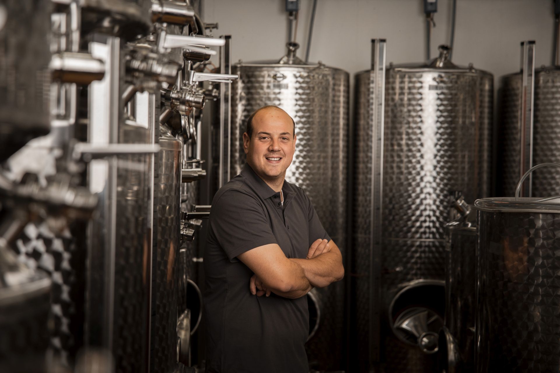 Mann in einem Weinkeller mit Edelstahlfässern.