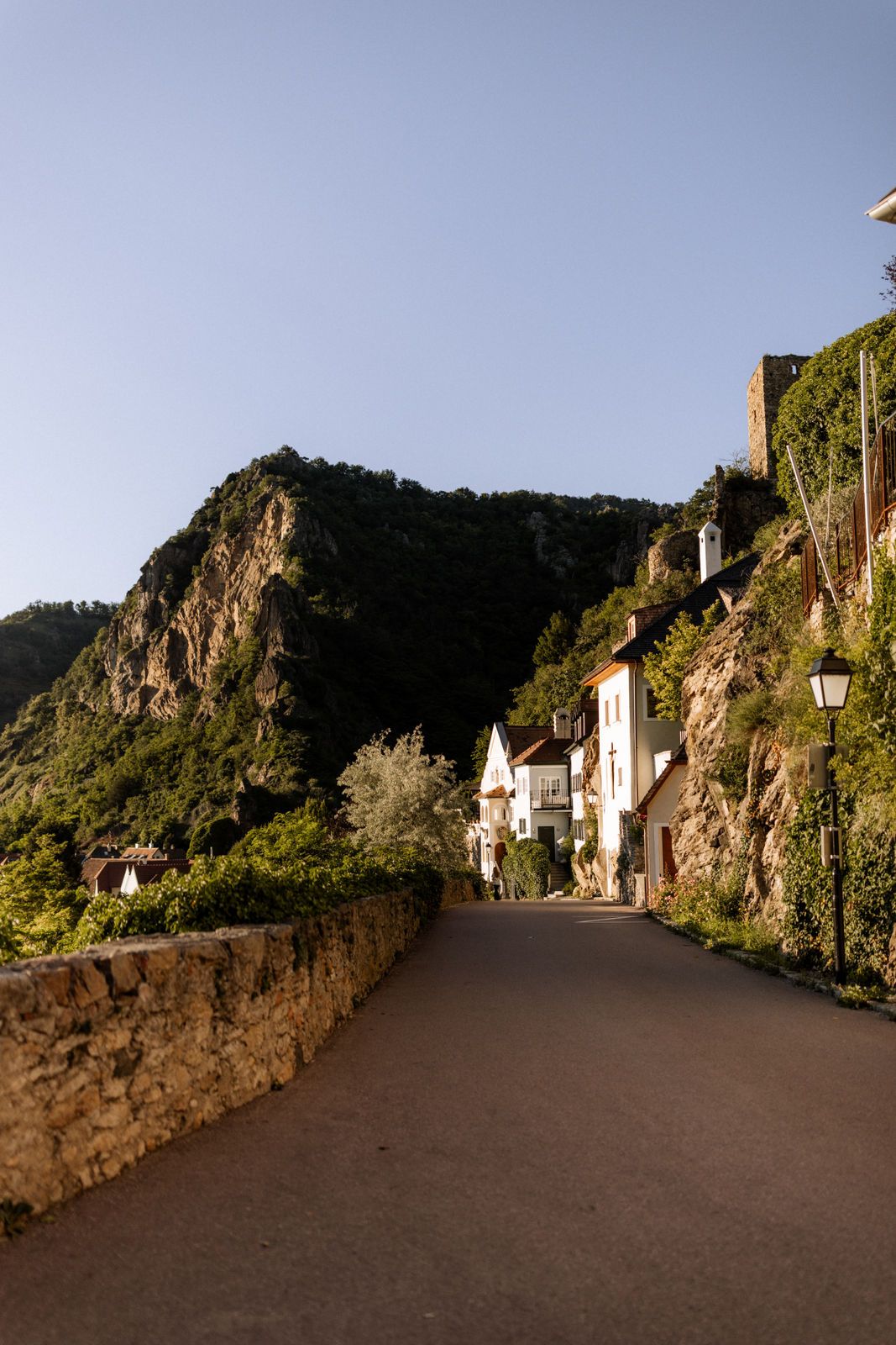 Straße in Dürnstein mit Häusern und Felsen im Hintergrund.