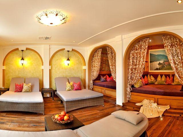 Ein gemütlicher Wellnessraum mit Liegen, Vorhängen und Kissen.