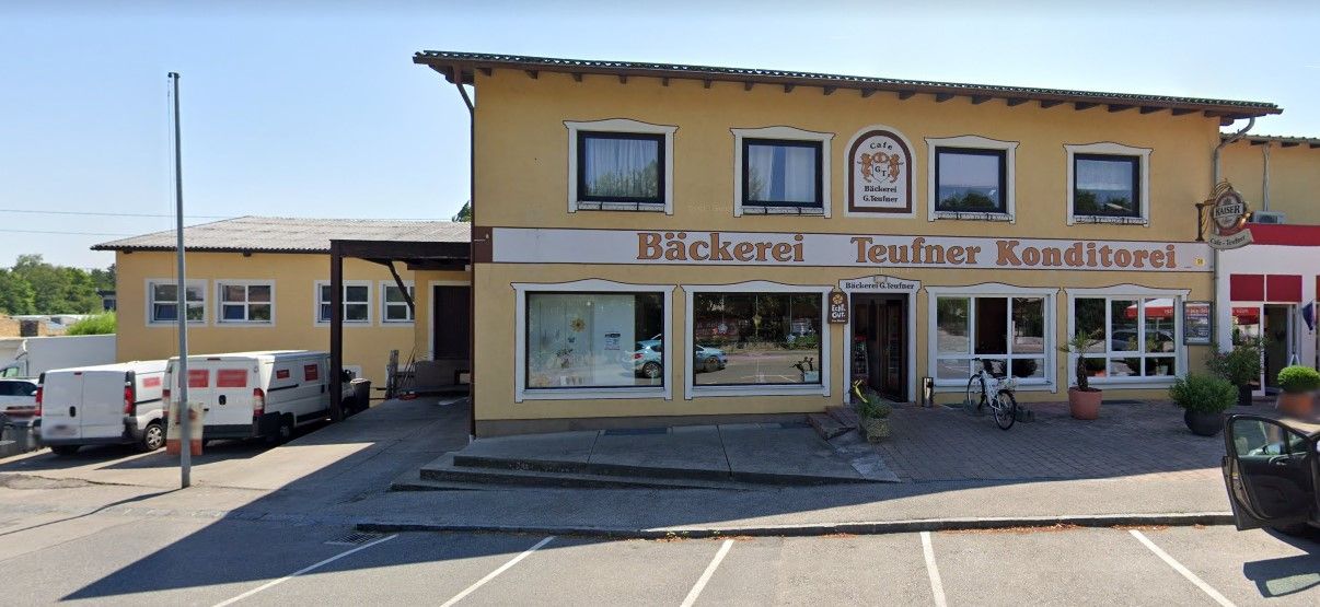 Außenansicht der Bäckerei Teufner mit gelber Fassade und Schaufenstern.