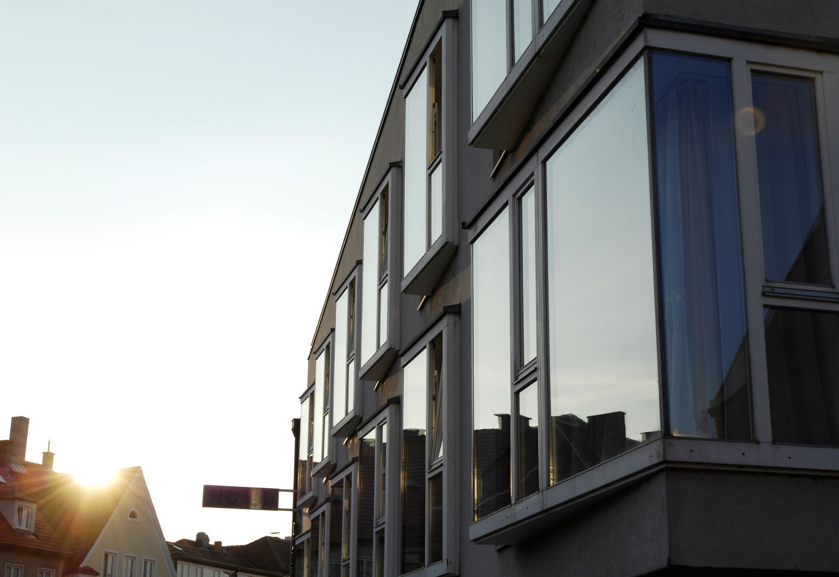 Moderne Gebäudefassade mit großen Fenstern im Sonnenuntergang.