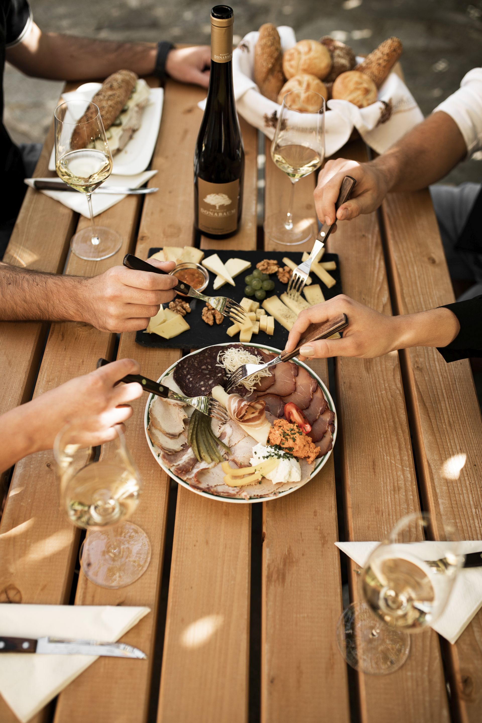 Ein Tisch mit Weinflasche, Gläsern, Käseplatte und Aufschnitt.