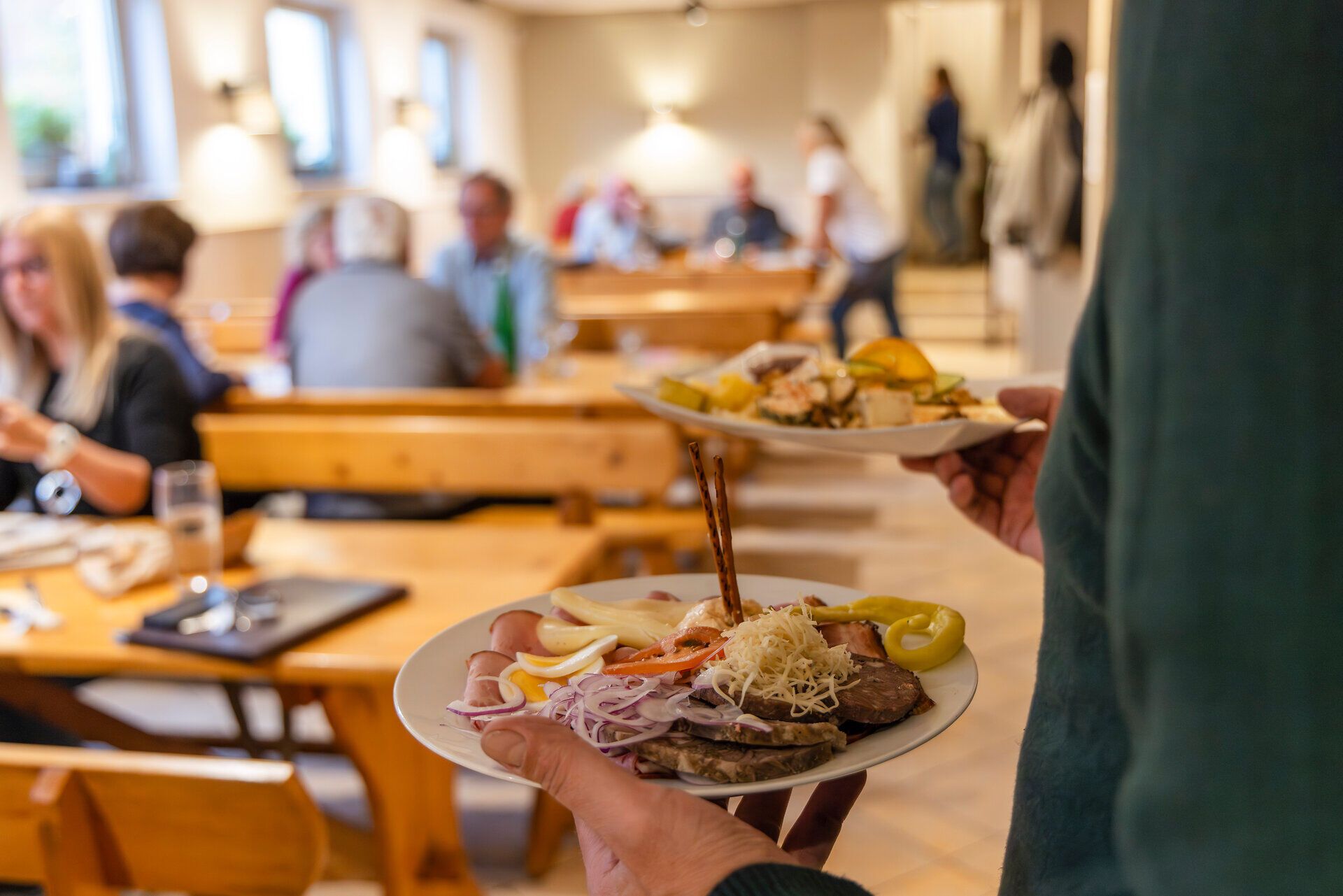 Heurigenplatten mit Fleisch werden an den Heurigentisch serviert. 