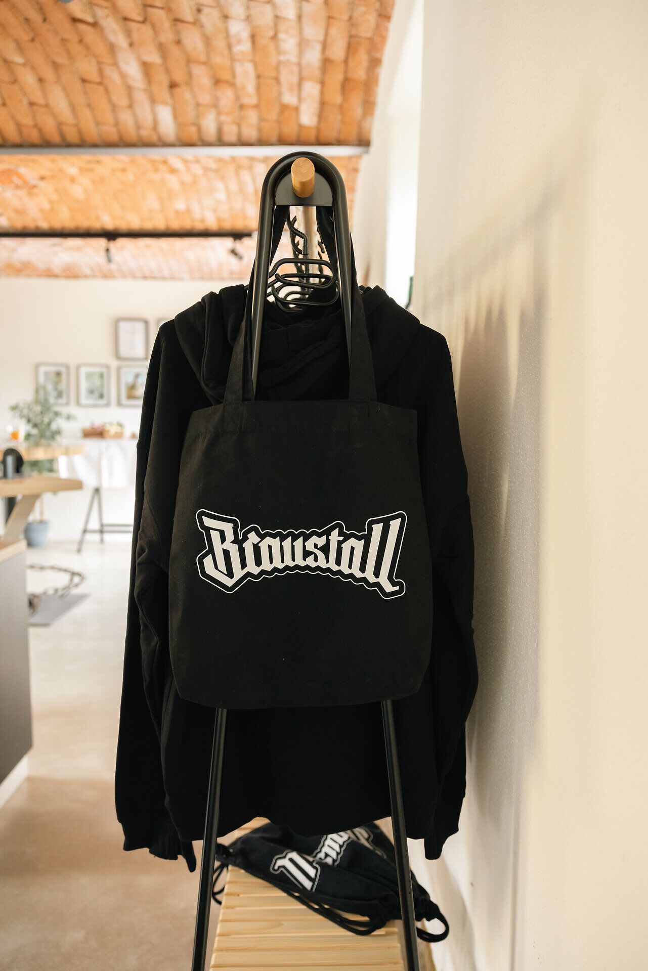 Schwarze Tasche mit Braustall-Logo vor schwarzer Kleidung.